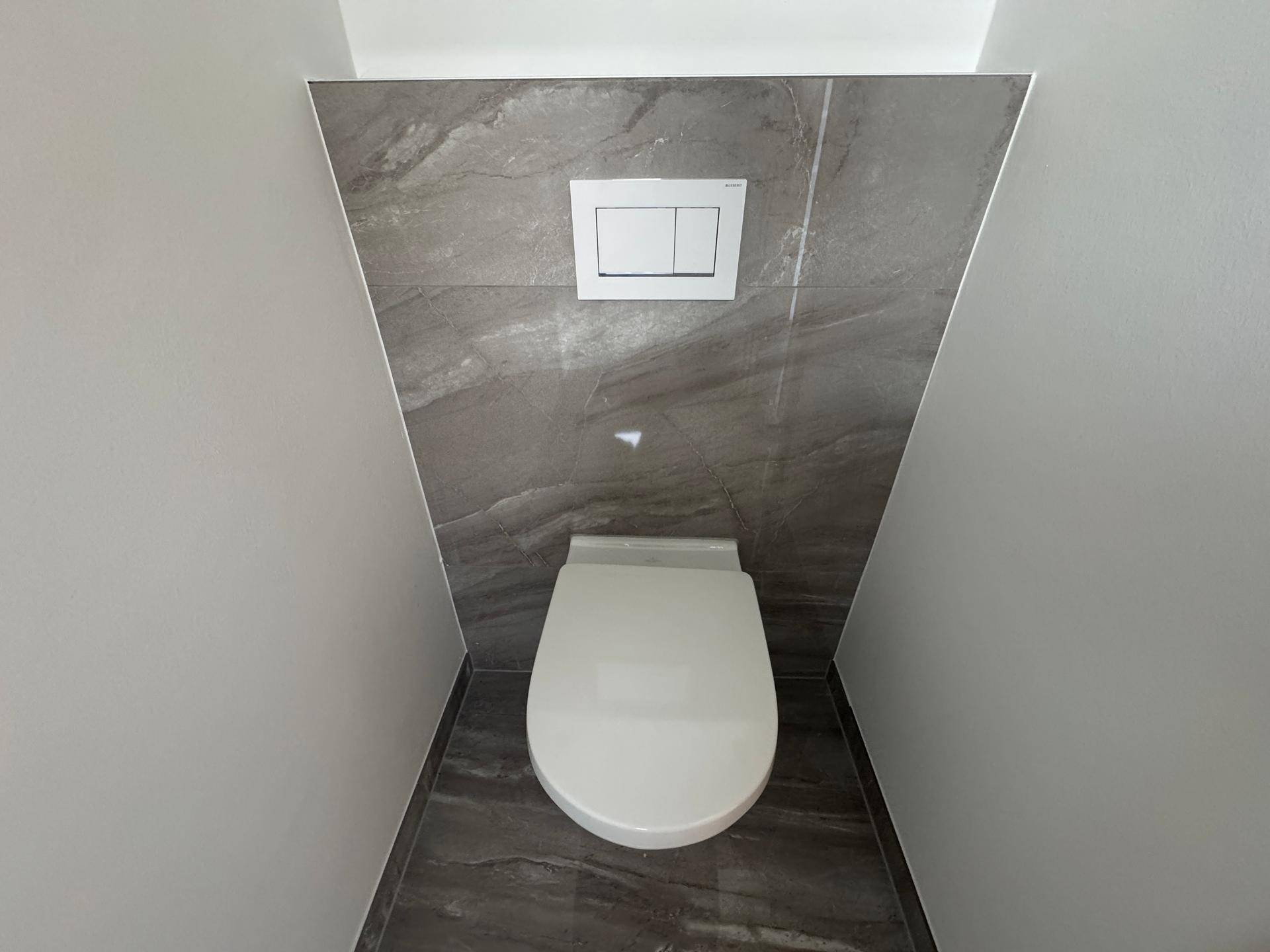 Wand-WC in einer Nische mit modernen grauen Fliesen.