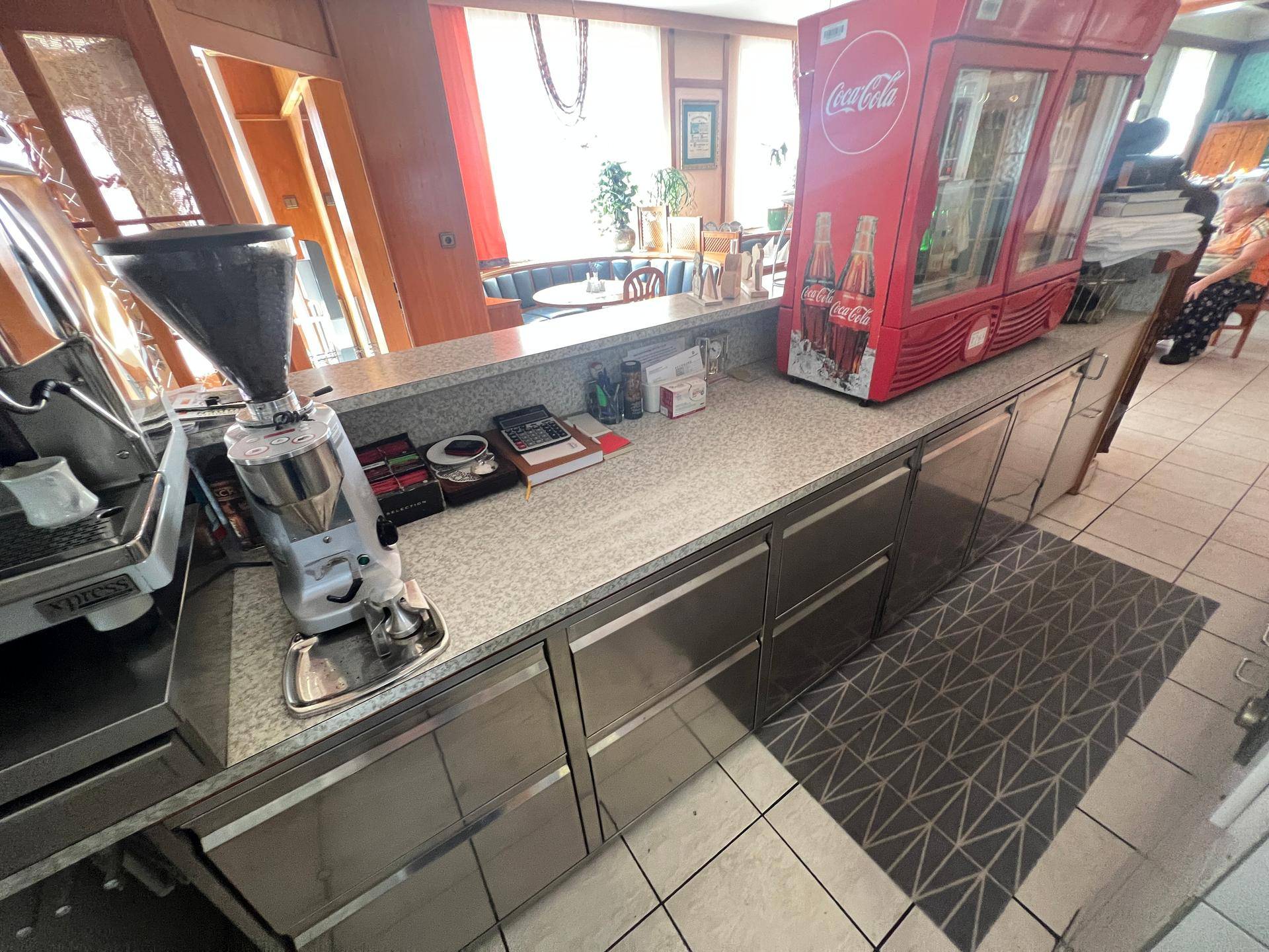 Arbeitsbereich einer Bar mit professioneller Kaffeemaschine, Kühlschrank und Edelstahlfronten.