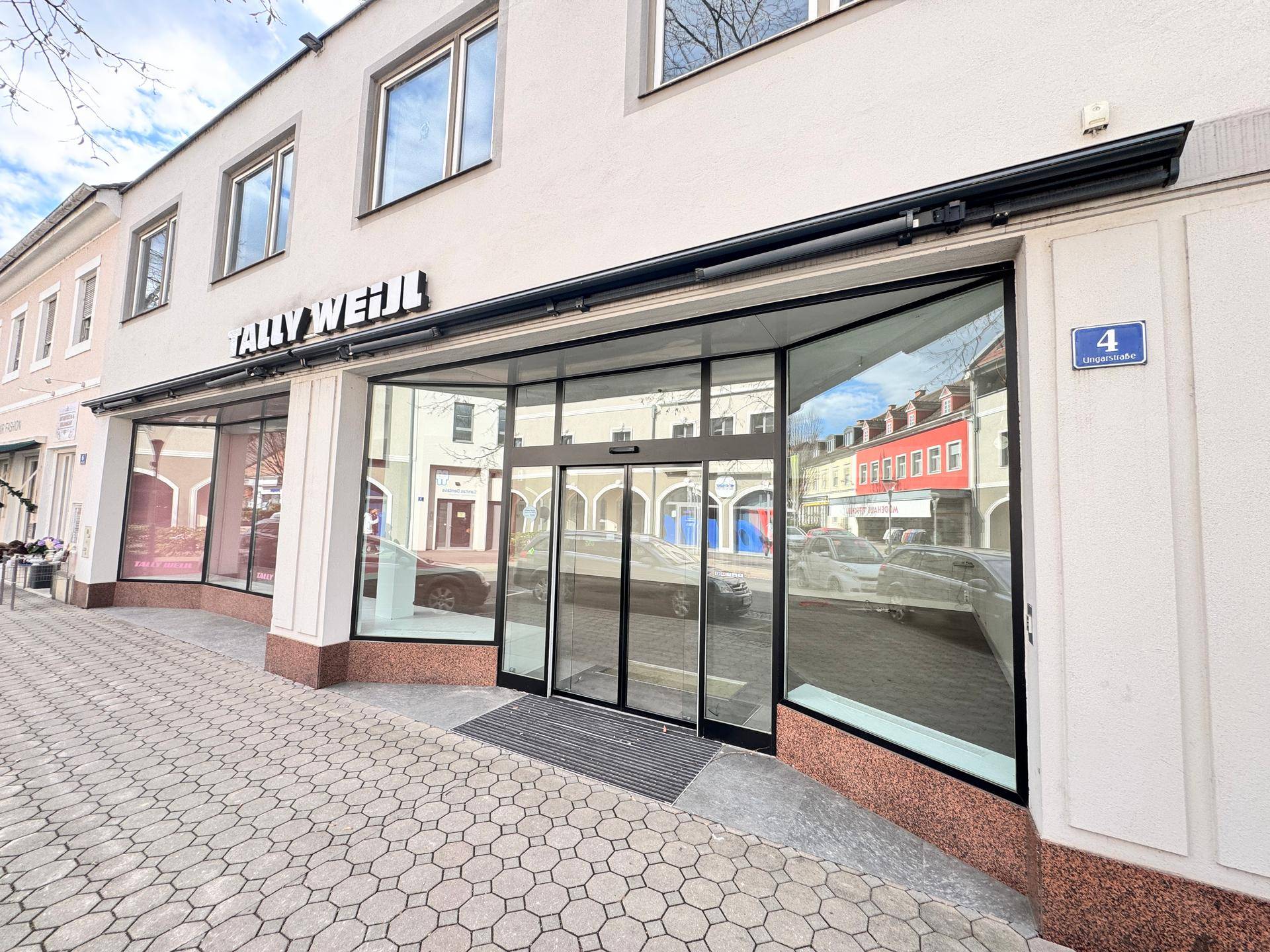 Eingangsbereich des Ladenlokals mit breiten Glasfronten und automatischer Schiebetür.