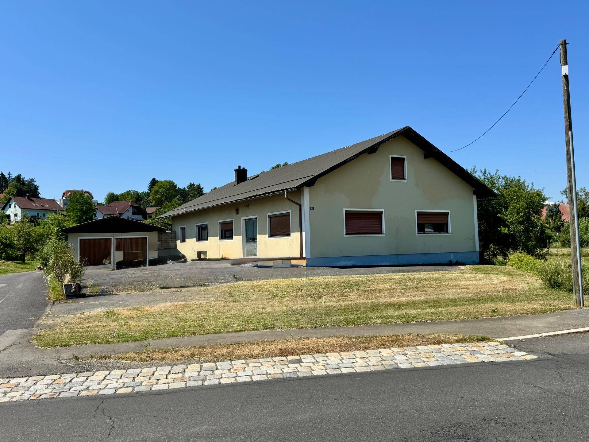 Ansicht des Einfamilienhauses mit angrenzender Garage und weitläufiger Grünfläche.