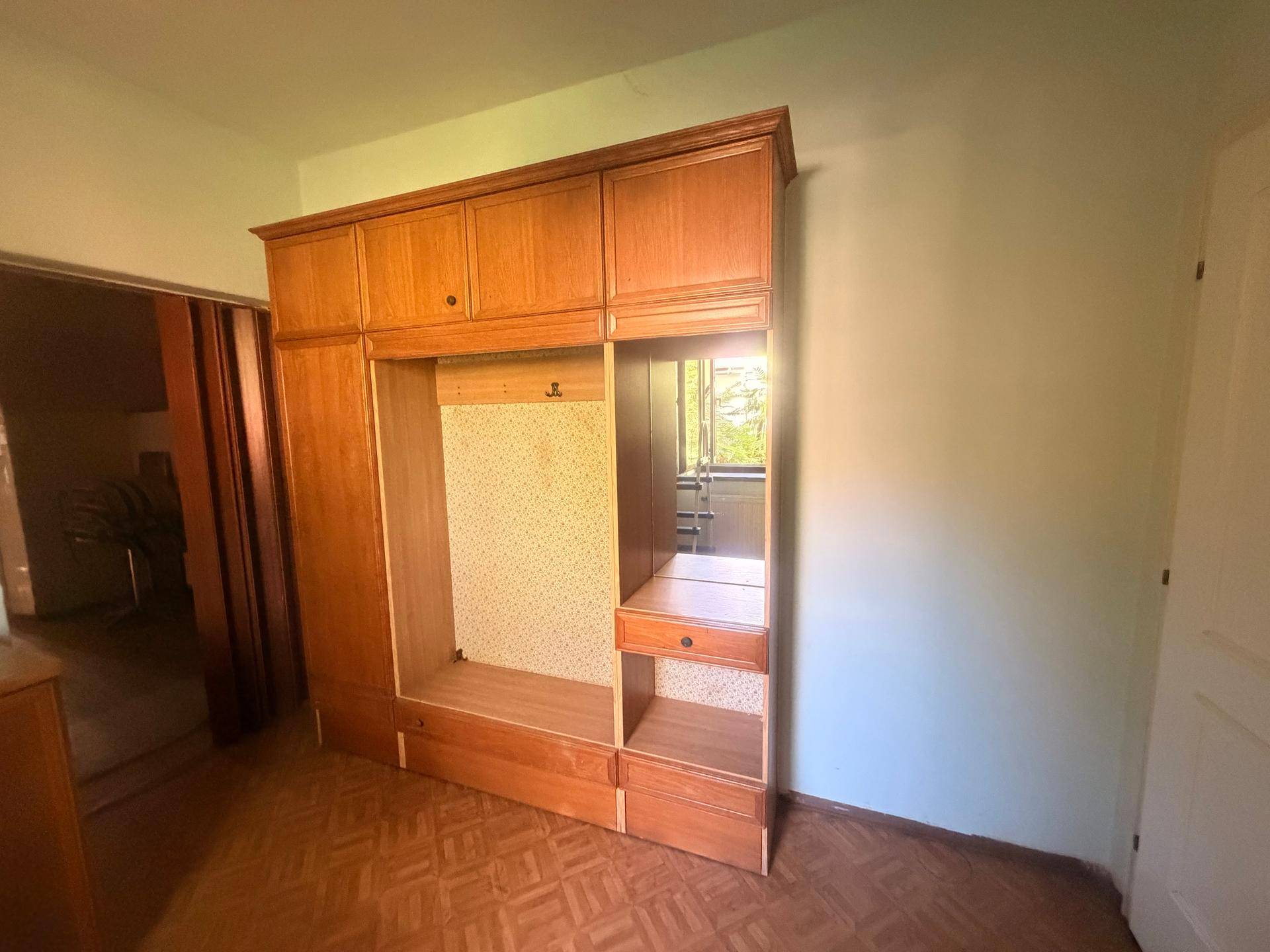 Zimmer mit großem Holzschrank und Parkettboden, ideal als Schlafzimmer oder Ankleide.