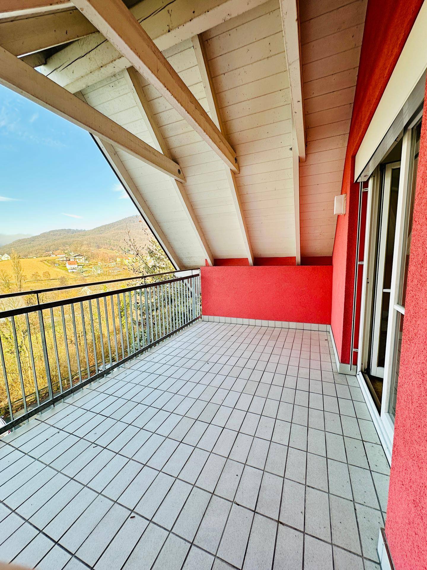 Überdachter Balkon mit Fliesenboden und weitem Blick über die umliegende Landschaft.
