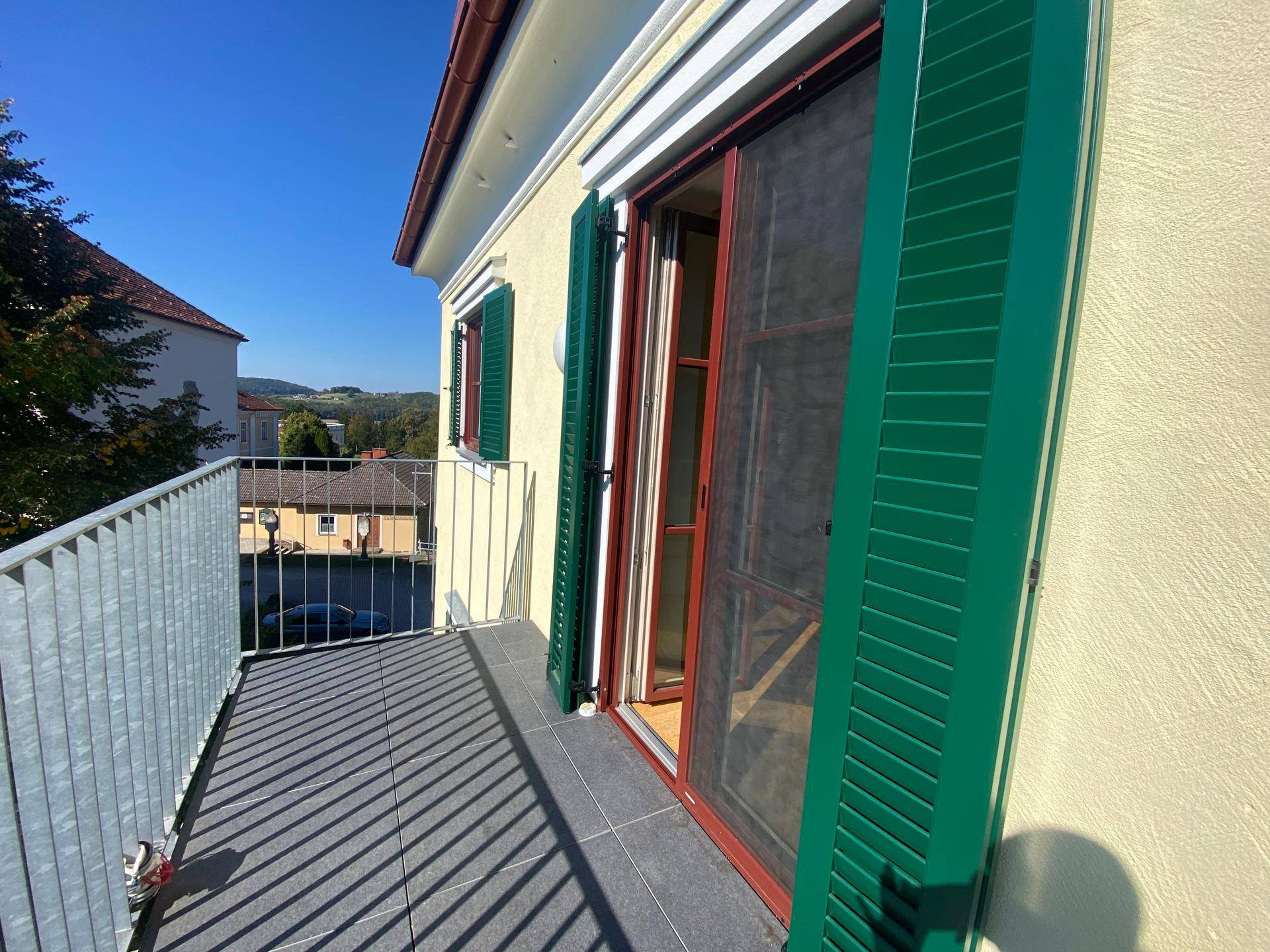 Balkon mit Fliesenboden, grünen Fensterläden und Blick auf die umliegende Nachbarschaft.