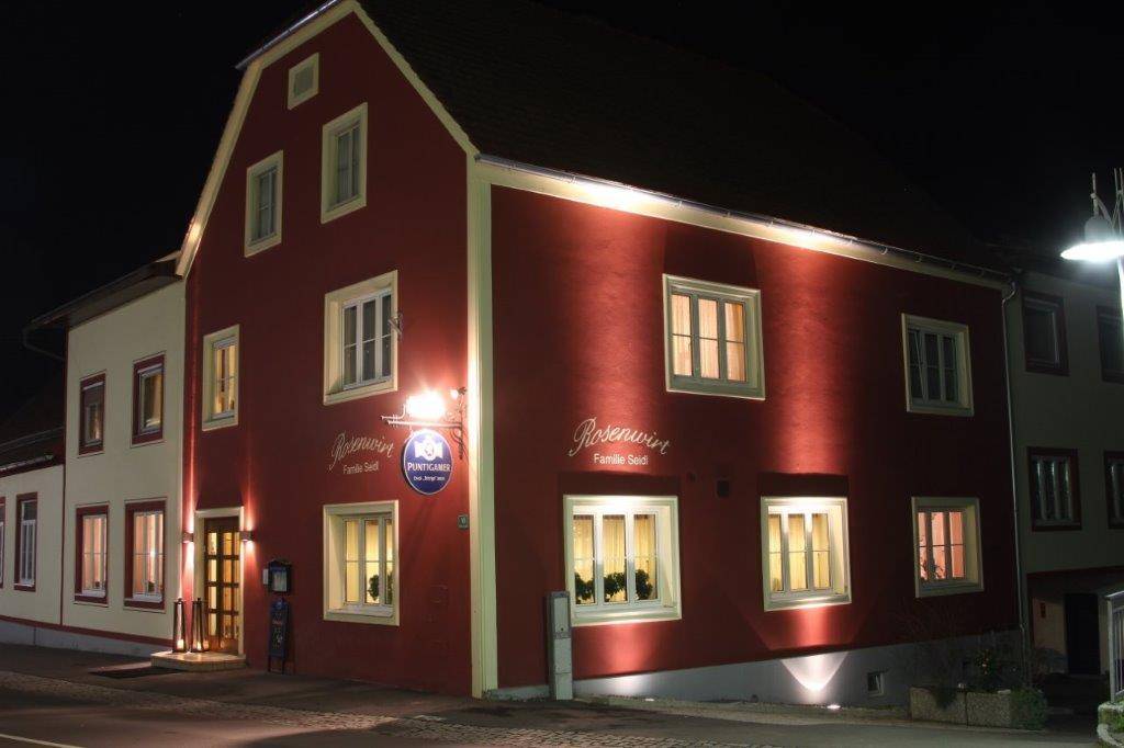 Außenansicht des Gebäudes bei Nacht mit akzentuierter Beleuchtung der Fassade.