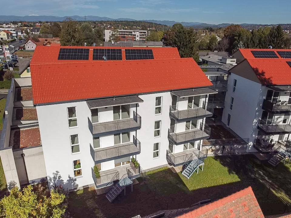 Vogelperspektive auf moderne Wohngebäude mit Balkonen und Photovoltaikanlagen auf den Dächern.