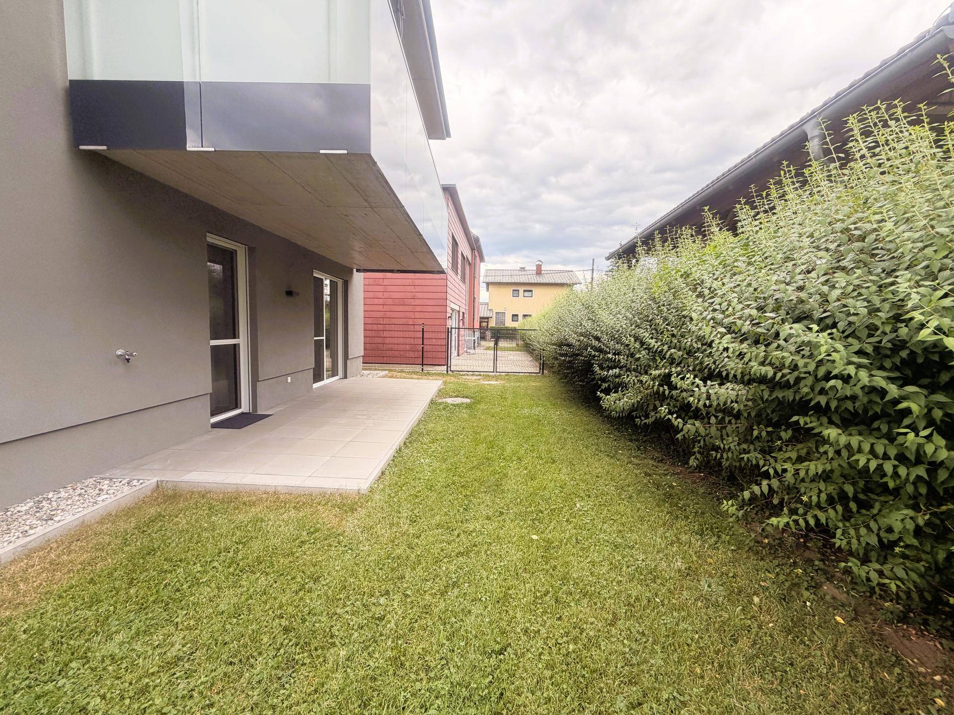 Gepflegter Gartenbereich neben dem Gebäude mit grüner Hecke.