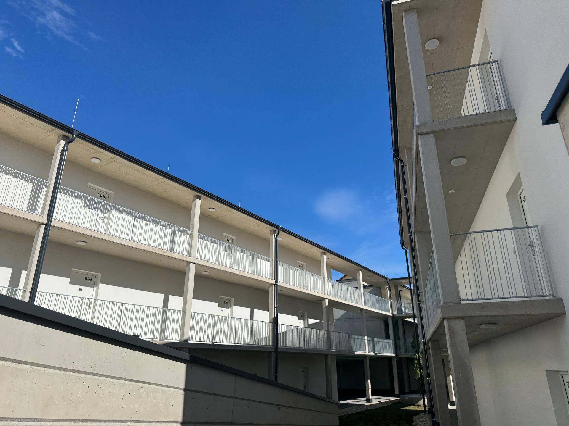 Begrünter Innenhof zwischen modernen Gebäuden mit Wegen und einem jungen Baum.