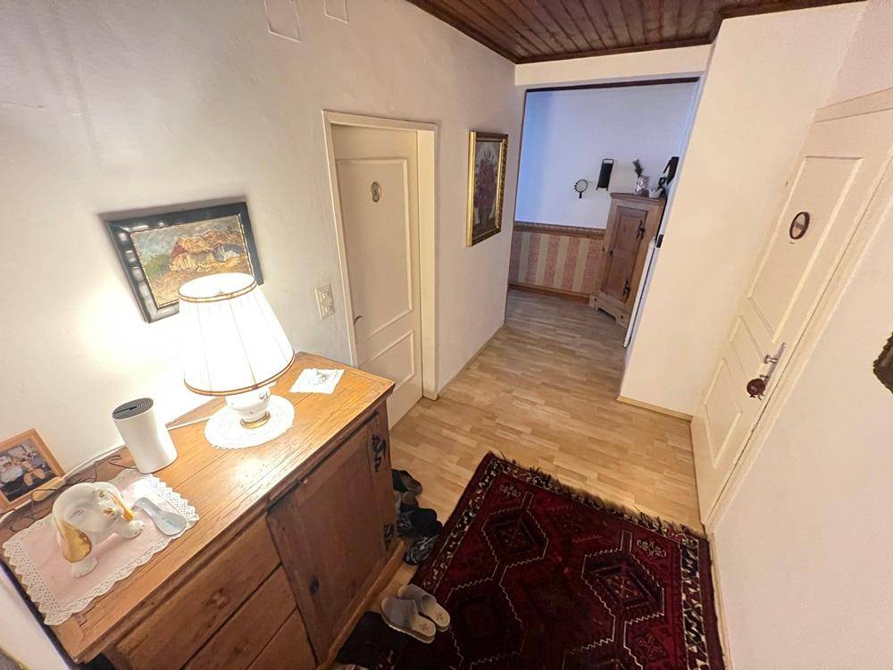 Flur mit Holzkommode, Teppich und Zugang zu verschiedenen Zimmern.