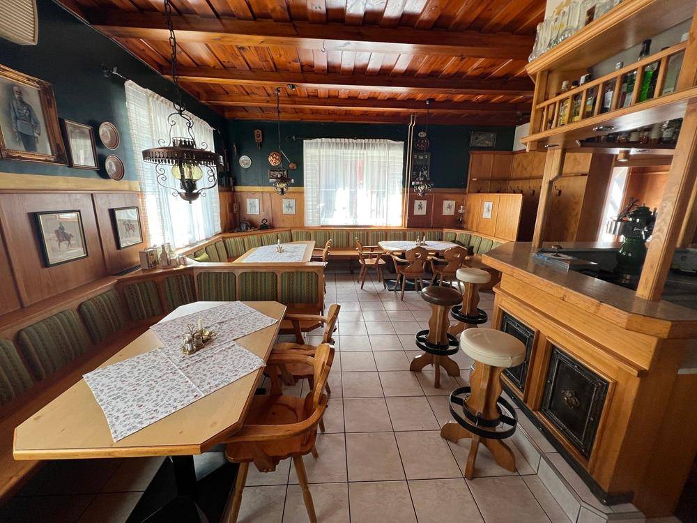Rustikaler Restaurantbereich mit Holzbänken, Tischen und einer einladenden Atmosphäre.
