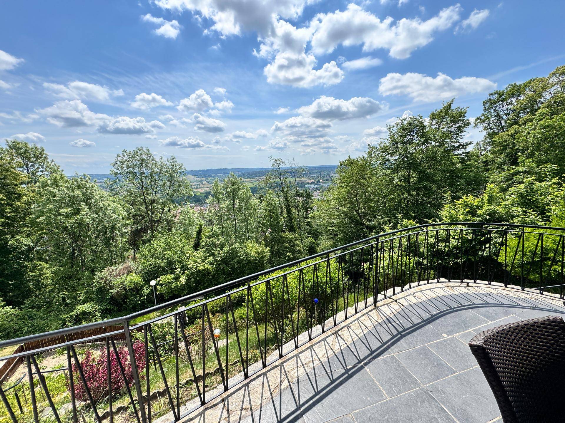 Geräumiger Balkon mit schmiedeeisernem Geländer und weitem Blick über die grüne Landschaft.