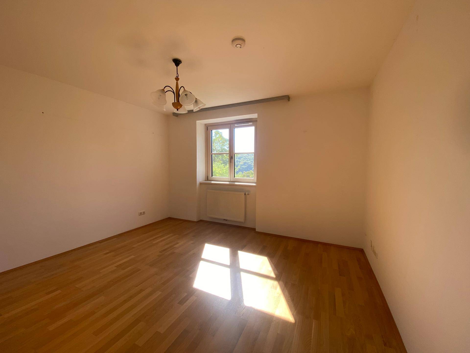 Helles Zimmer mit Holzboden, Fenster und Heizkörper, ideal als Schlaf- oder Arbeitszimmer.