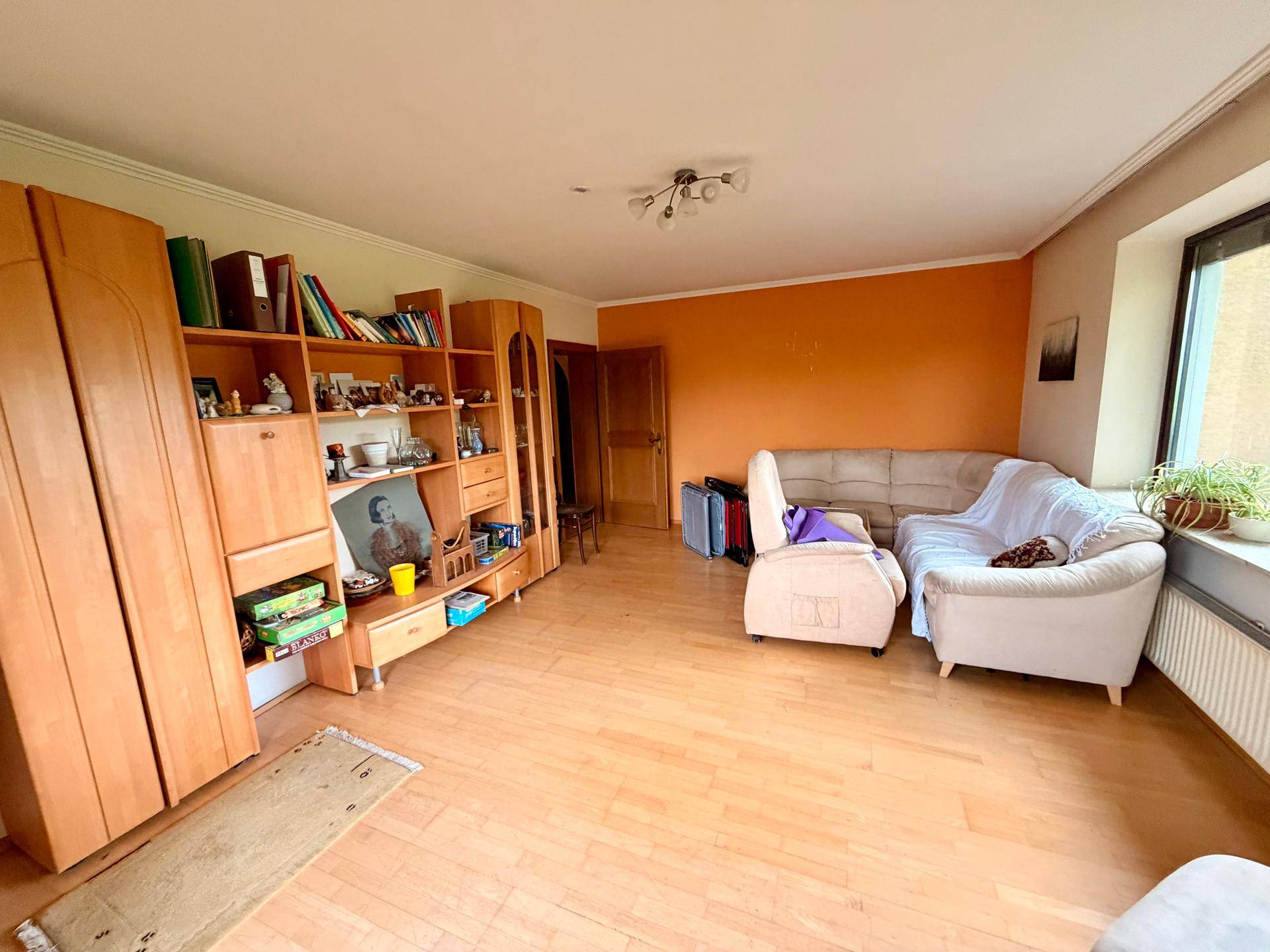 Geräumiges Wohnzimmer mit Laminatboden, Holzregalen und bequemen Sofas.