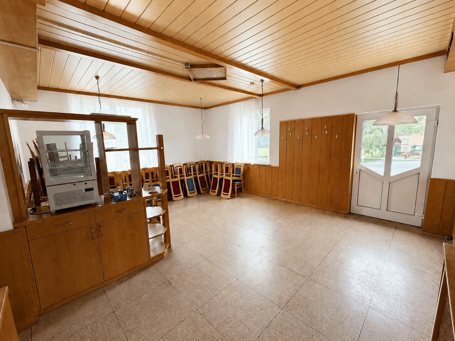 Ein traditioneller Speisesaal mit Holzvertäfelung, hellen Wänden und vielen Stühlen, bereit für Gäste.
