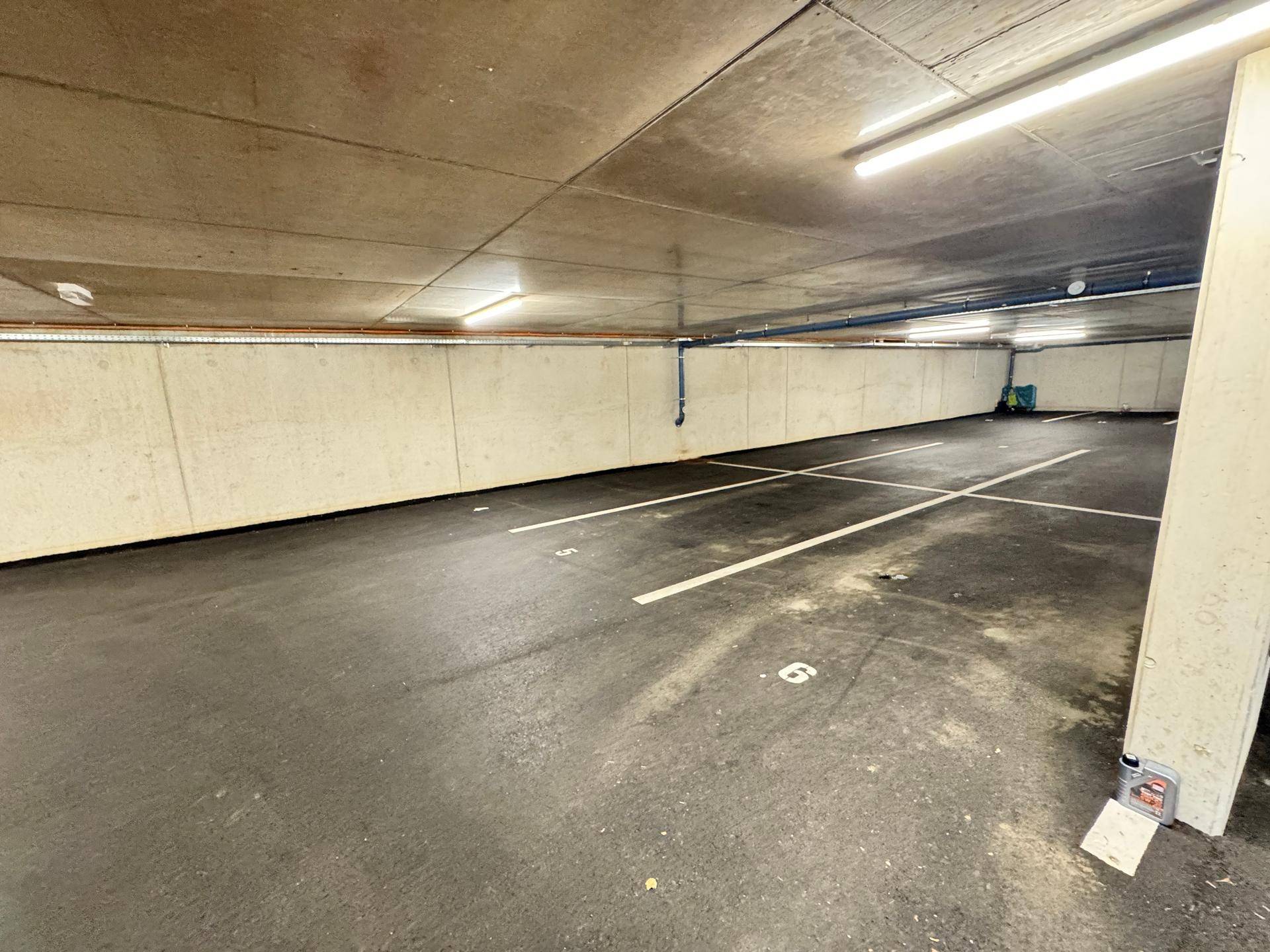Leere Tiefgarage mit Betonwänden und markierten Parkplätzen, bereit zur Nutzung.