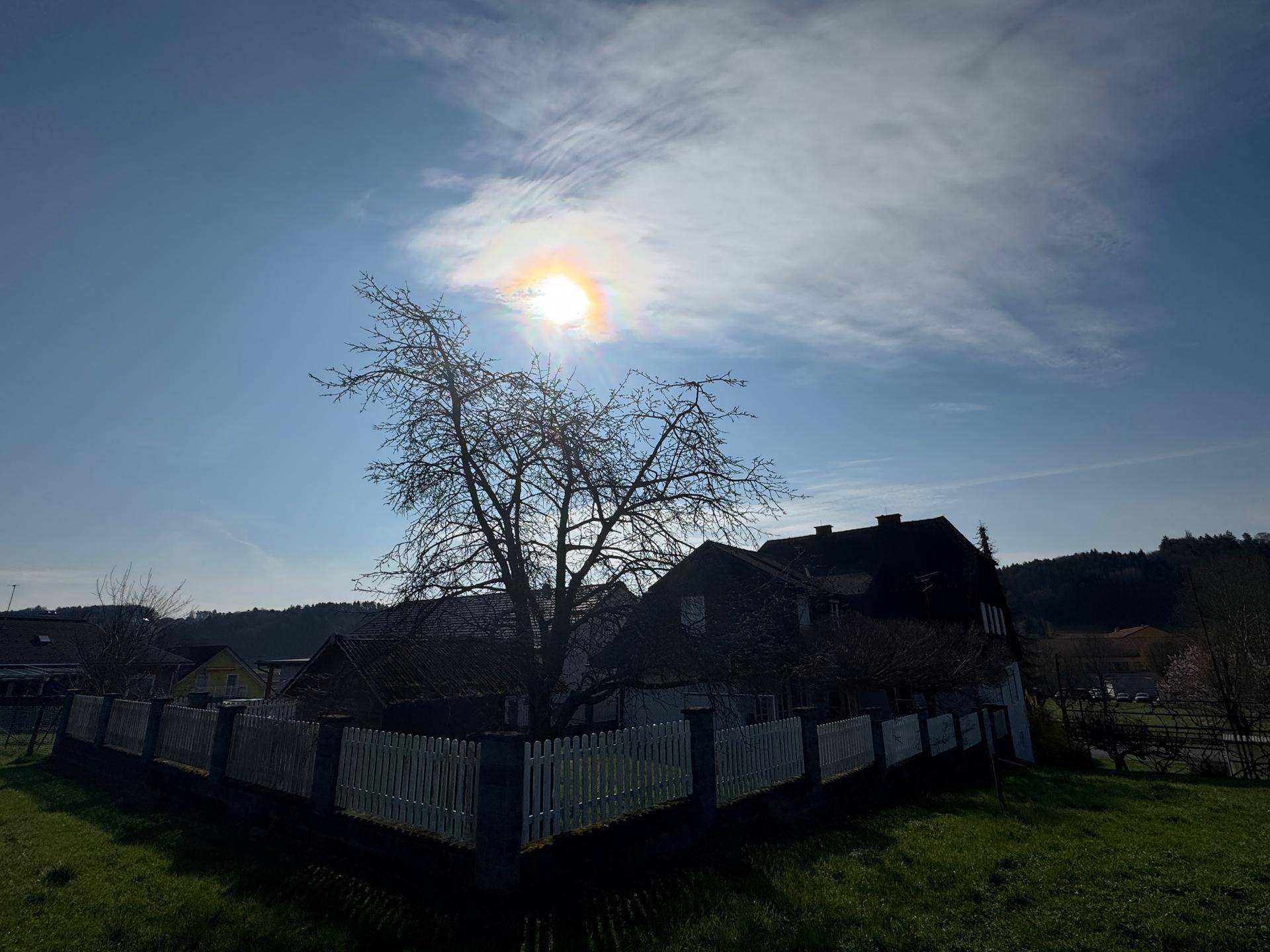 Weitläufige Landschaftsaufnahme mit dem Haus im Hintergrund und strahlendem Sonnenschein.