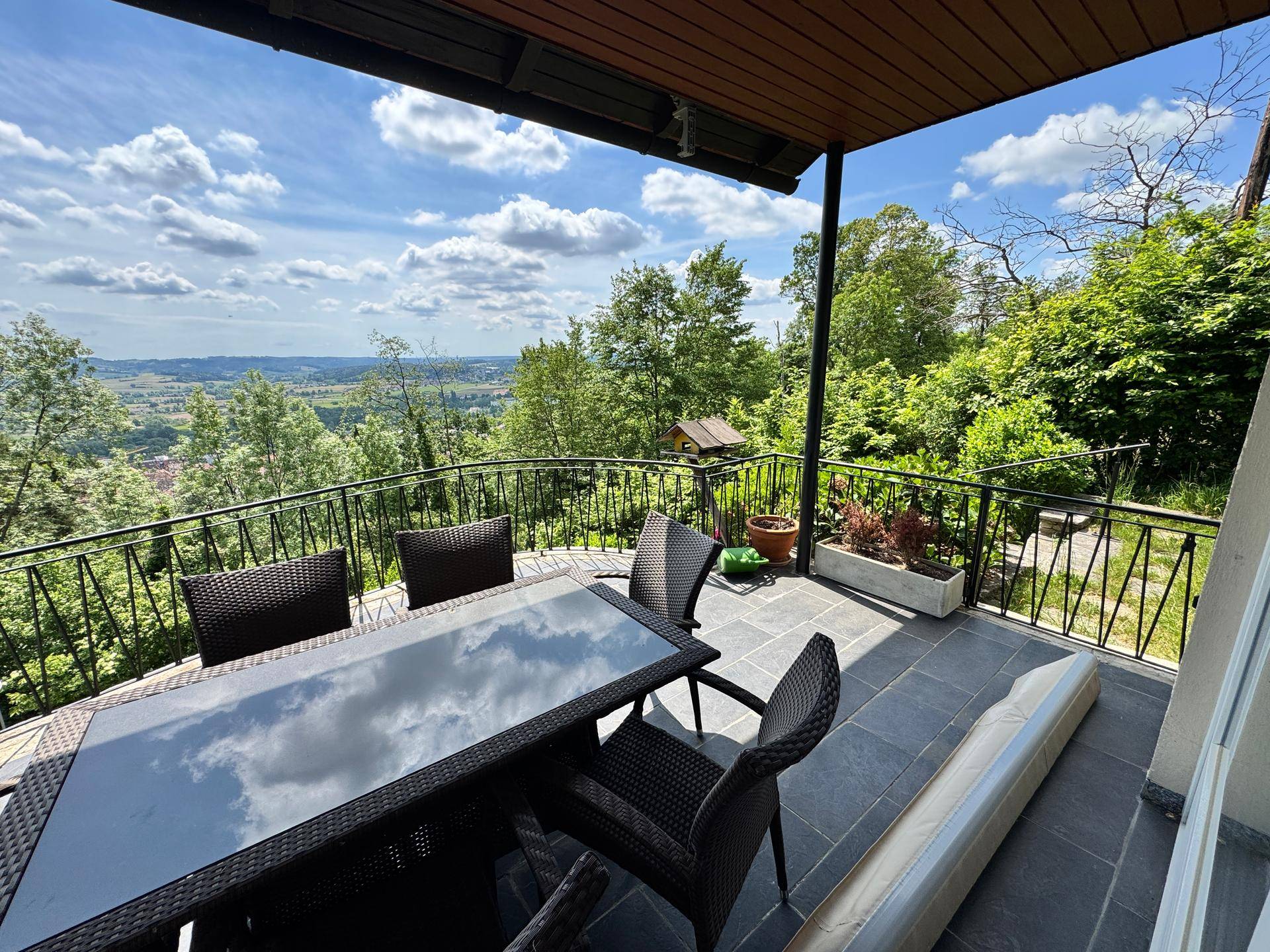 Möblierter Balkon mit Esstisch und Stühlen, bietet einen weiten Blick über die Landschaft.