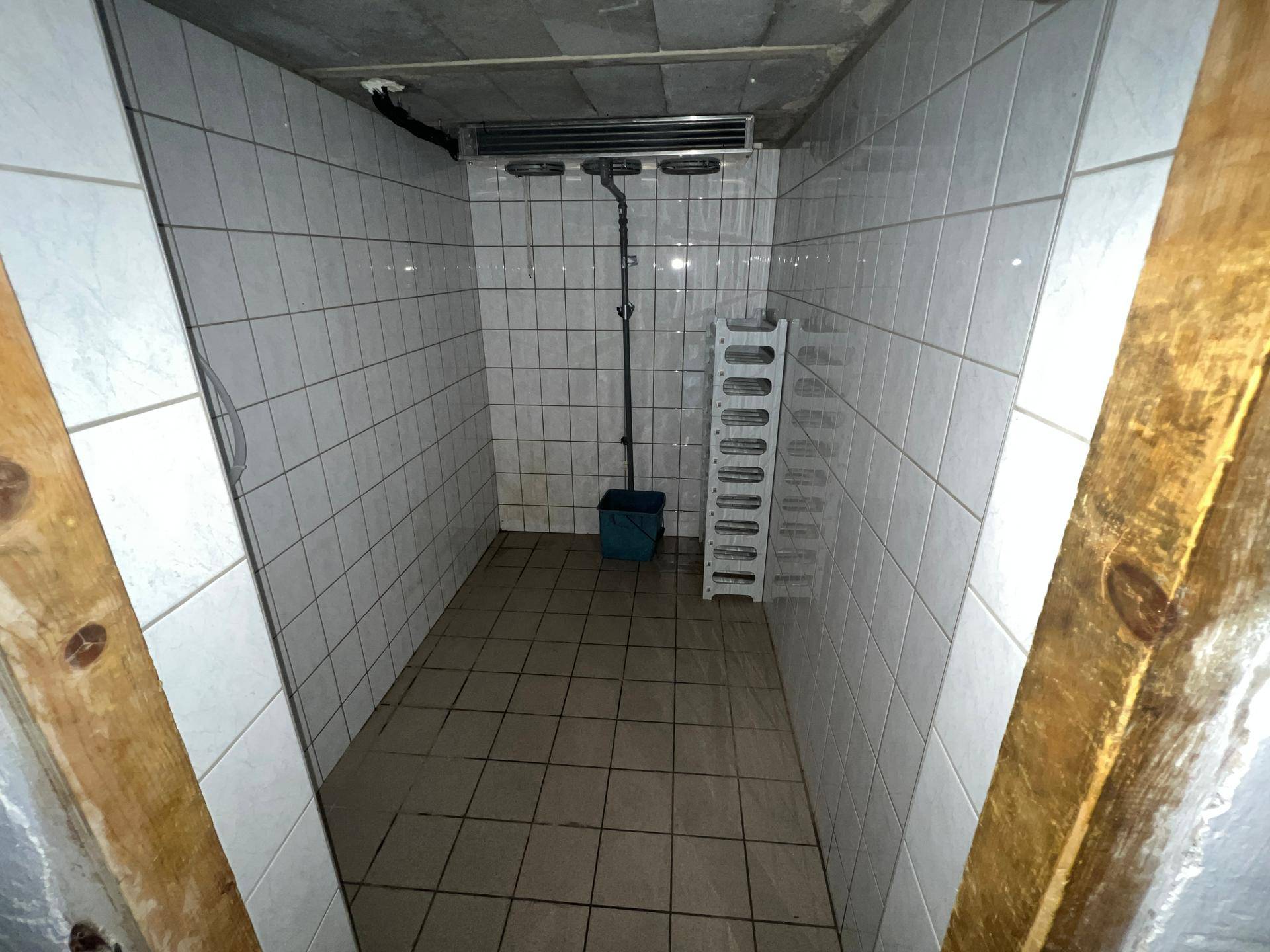 Gefliester Lagerraum mit Regalen und Kühlaggregat an der Decke, ideal für Vorräte.