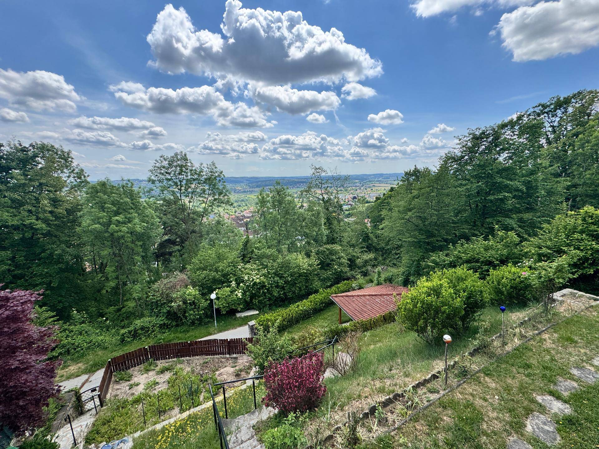 Weitläufiger Garten mit Steinstufen und üppiger Vegetation, bietet einen malerischen Blick ins Tal.
