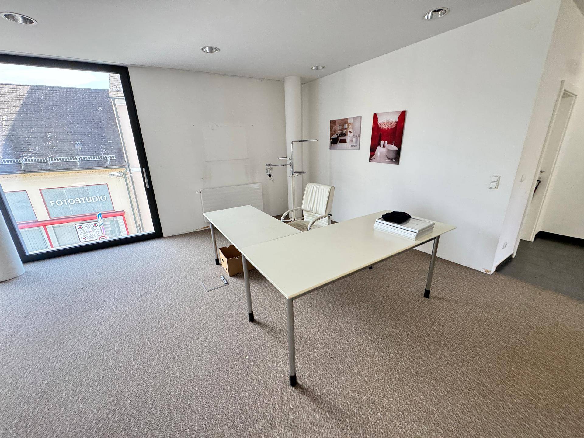 Helles Büro mit Teppichboden und großen Fenstern, bietet eine angenehme Arbeitsumgebung und viel Tageslicht.