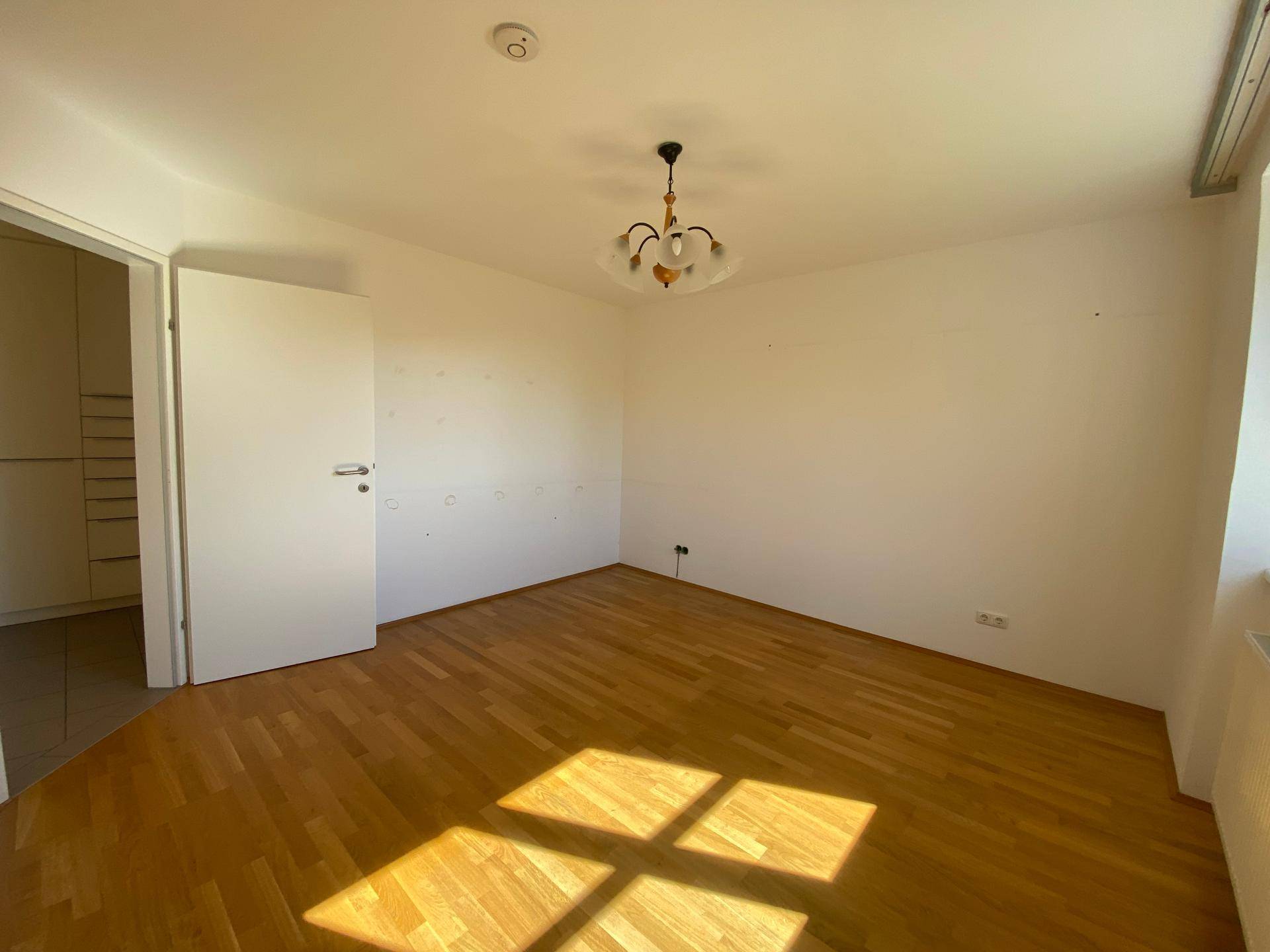 Geräumiges Schlafzimmer mit Holzboden und viel Tageslicht, bereit zur individuellen Gestaltung.