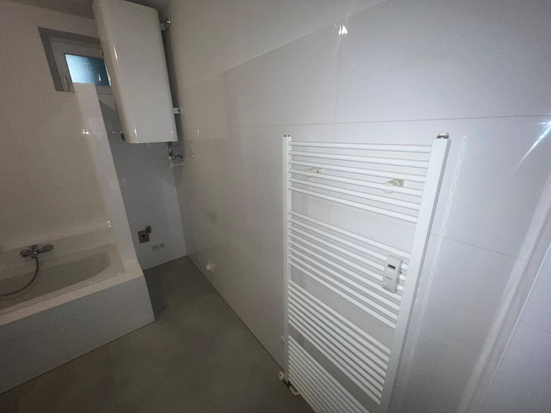 Modernes Badezimmer mit Badewanne, Heizkörper und weißen Wandfliesen.