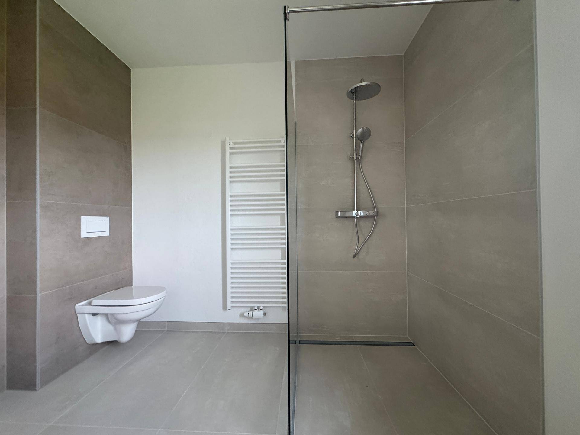 Modernes Badezimmer mit ebenerdiger Dusche, Wand-WC und beheiztem Handtuchhalter.