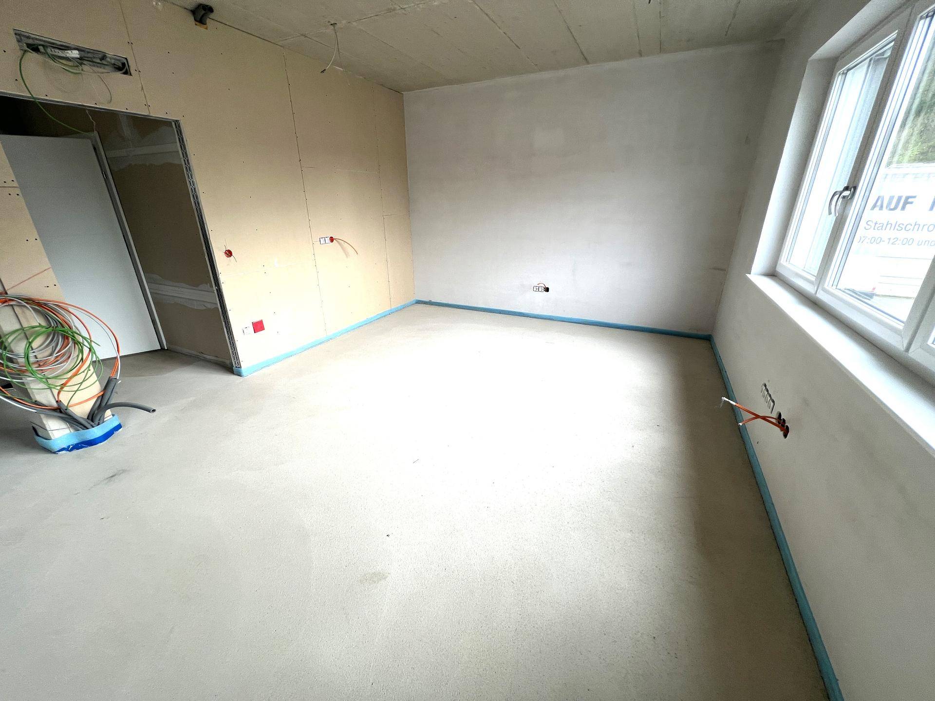 Raum im Rohbau mit Betonboden und vorbereiteten Wänden, bereit für die weitere Gestaltung.