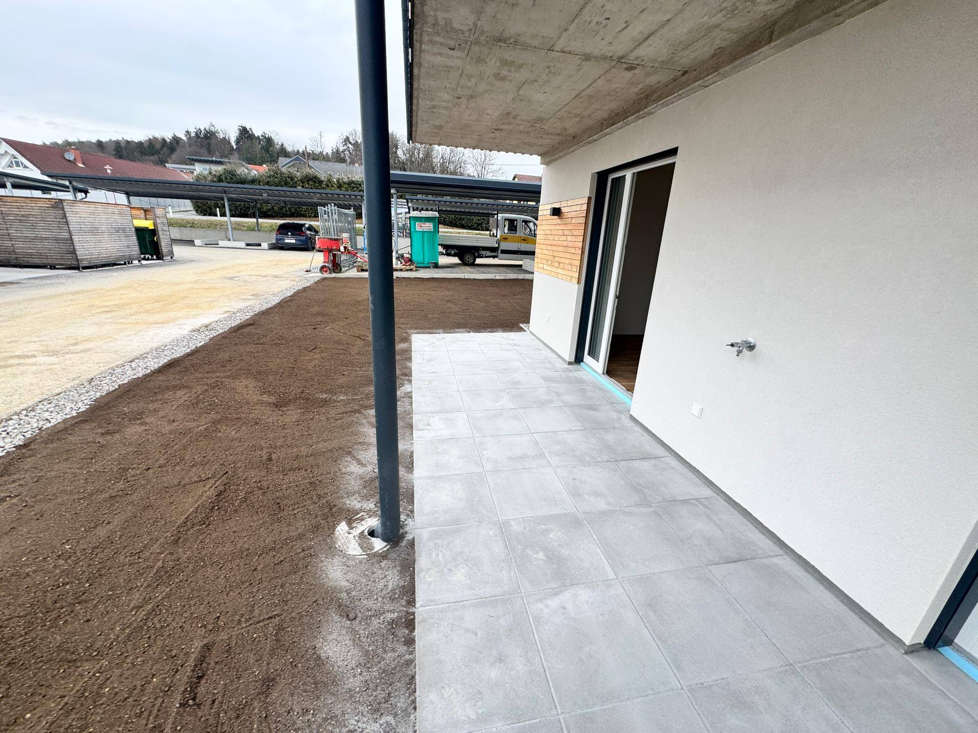 Gepflasterte Terrasse im Erdgeschoss mit Zugang zum Gartenbereich und Blick auf die Umgebung.