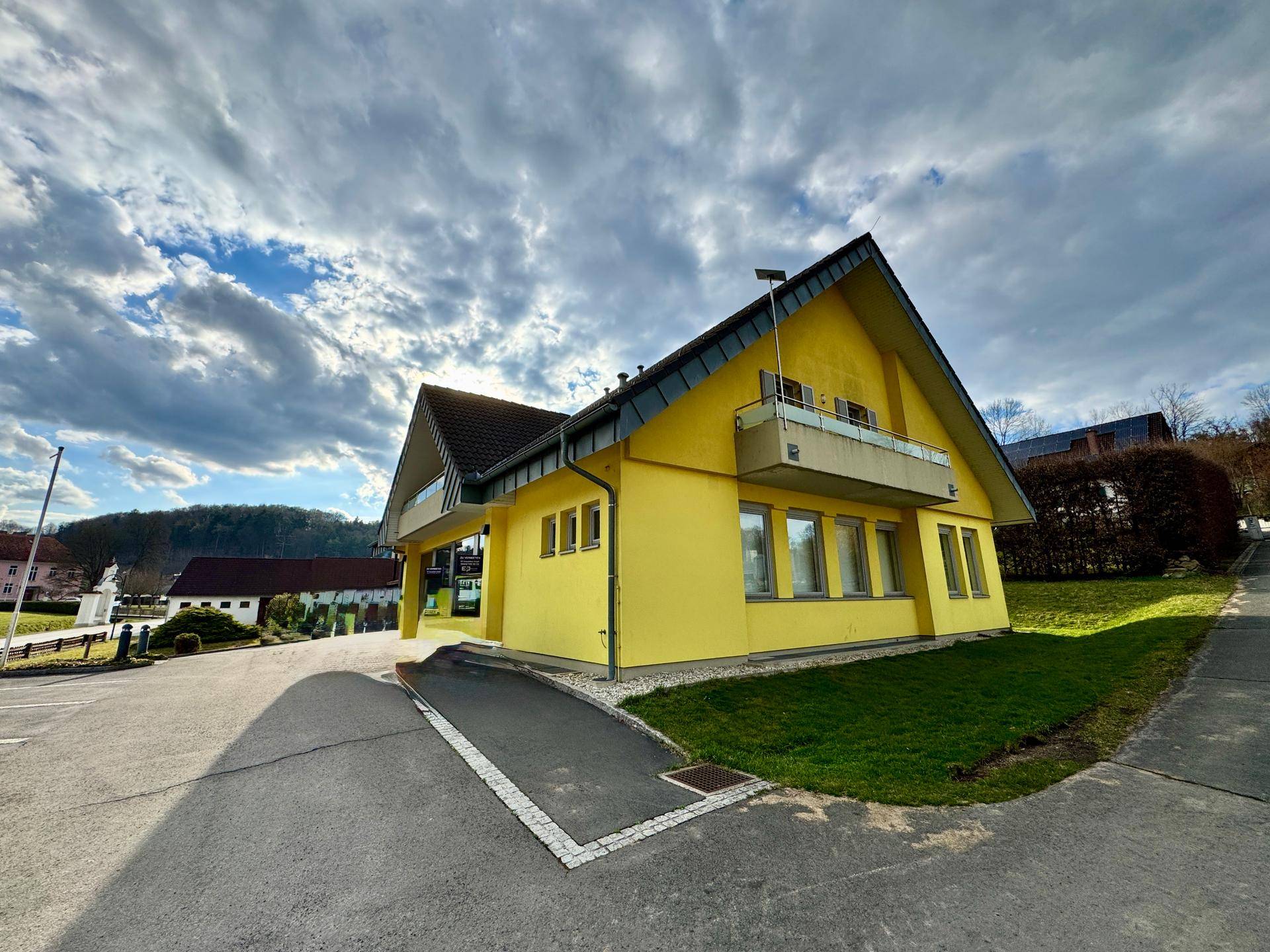 Seitenansicht des gelben Gebäudes mit Parkplatz und Rampe unter blauem Himmel.