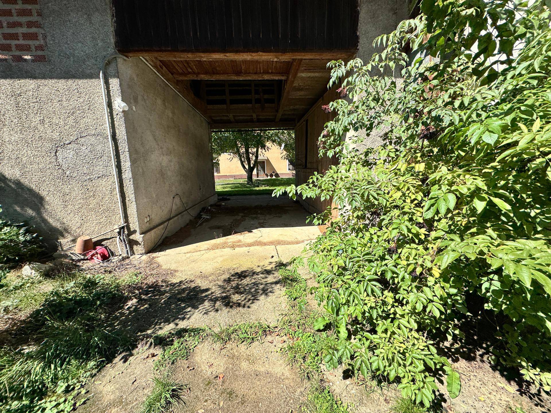 Überdachter Durchgang oder Carport mit Blick auf das Hauptgebäude.