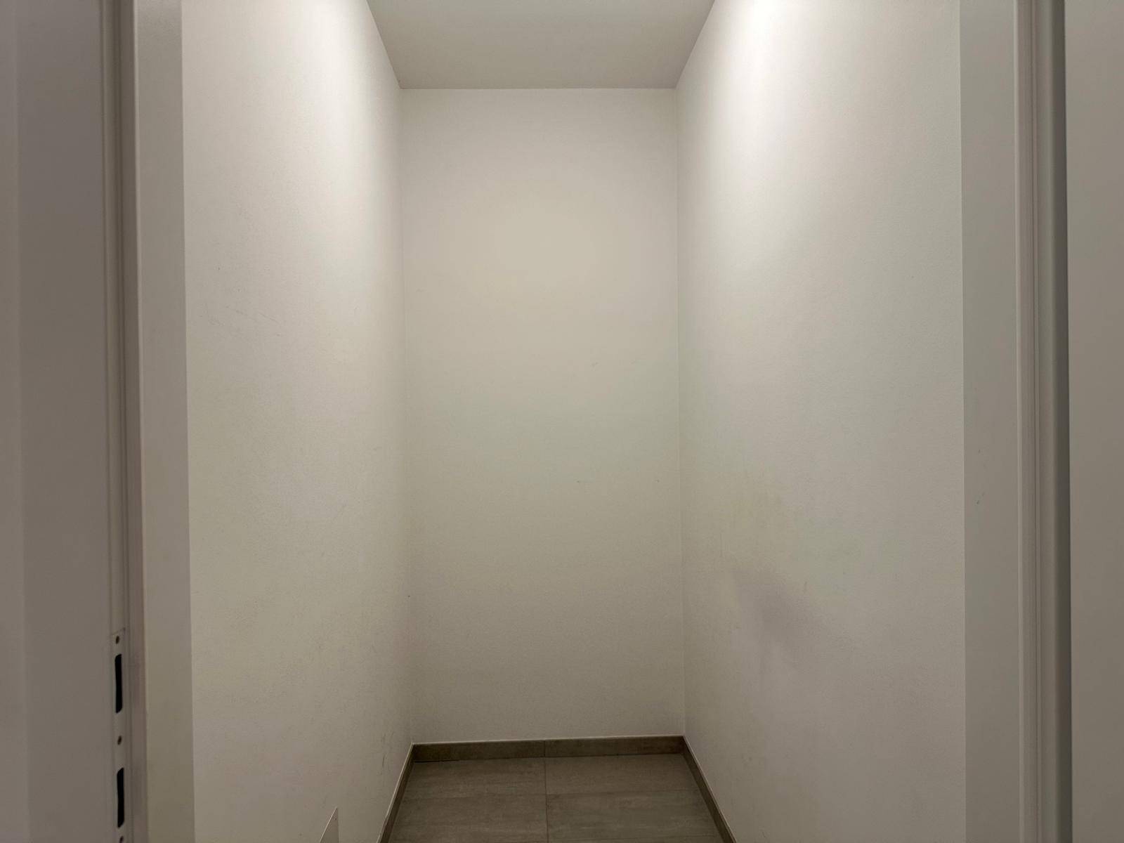Praktischer Abstellraum mit Fliesenboden und weißen Wänden für zusätzlichen Stauraum.