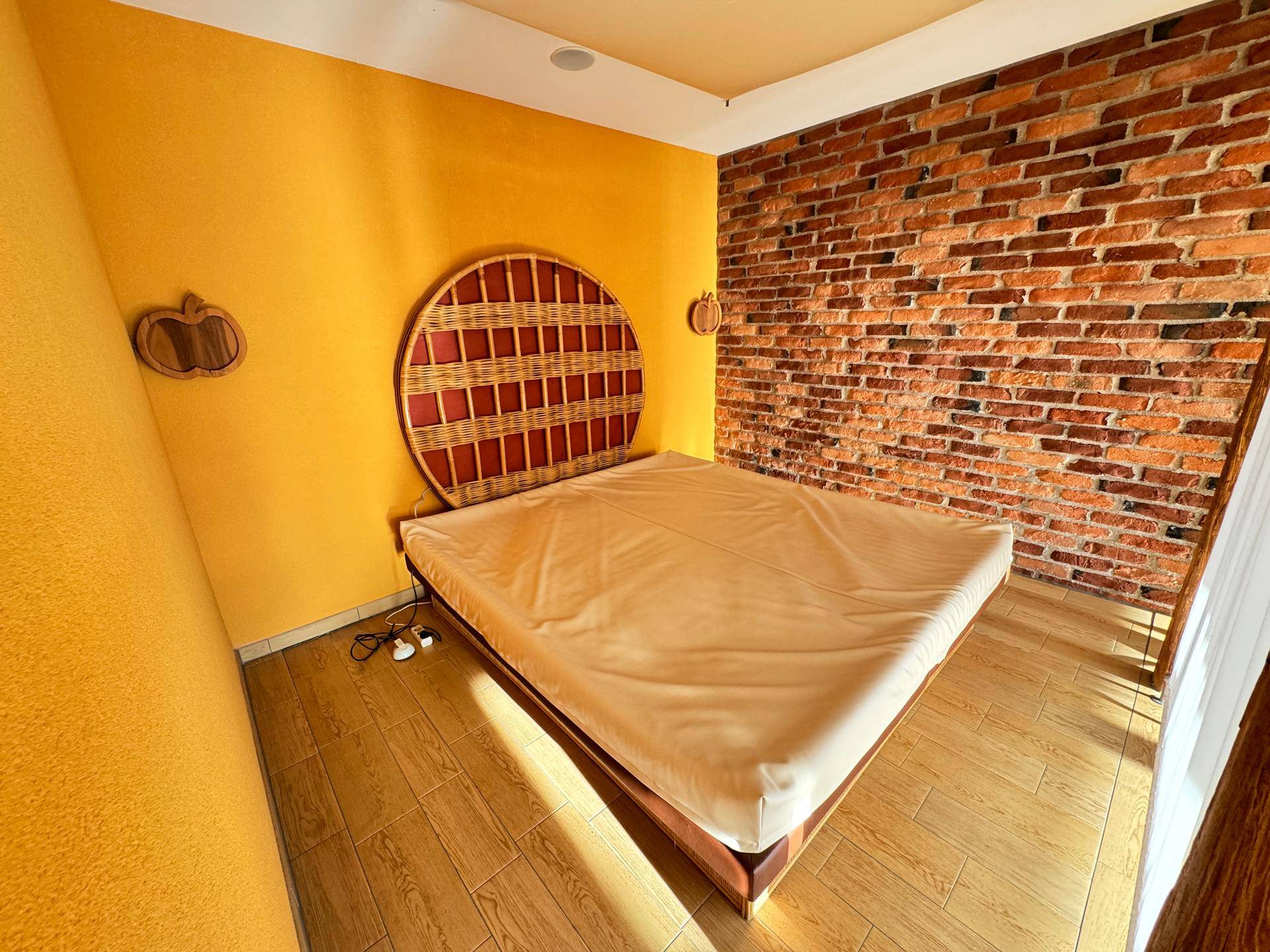 Schlafzimmer mit Ziegelwand, Holzboden und großem Bett.