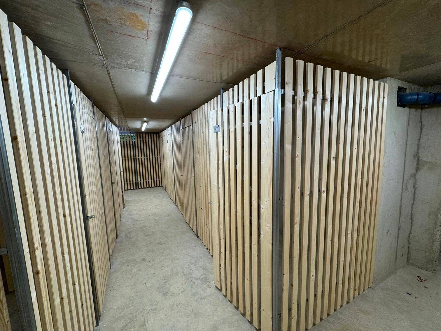 Kellerabteile mit Holzlattenwänden bieten praktischen Stauraum im Untergeschoss.