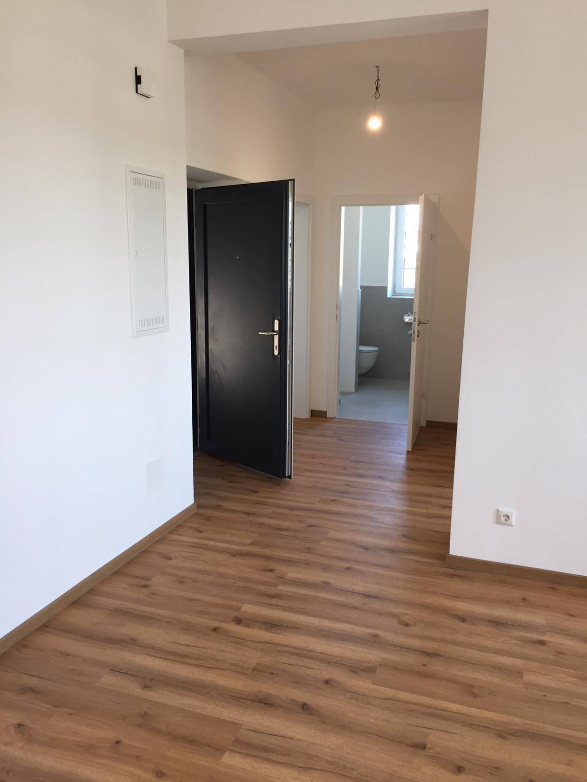 Heller Flur mit Laminatboden und Zugang zu weiteren Räumen und einem Badezimmer.