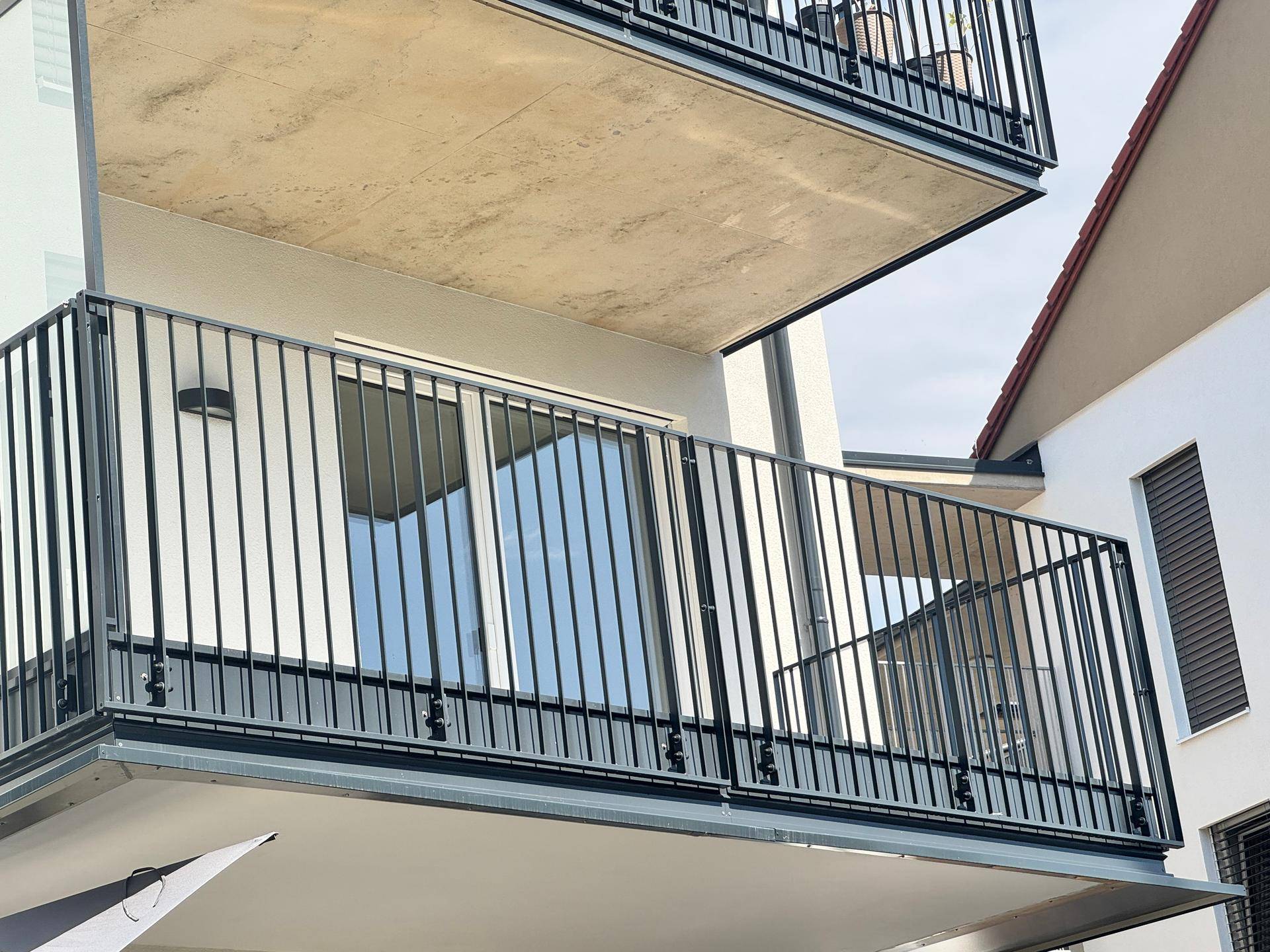 Moderne Gebäudefassade mit mehreren Balkonen und schwarzen Metallgeländern.