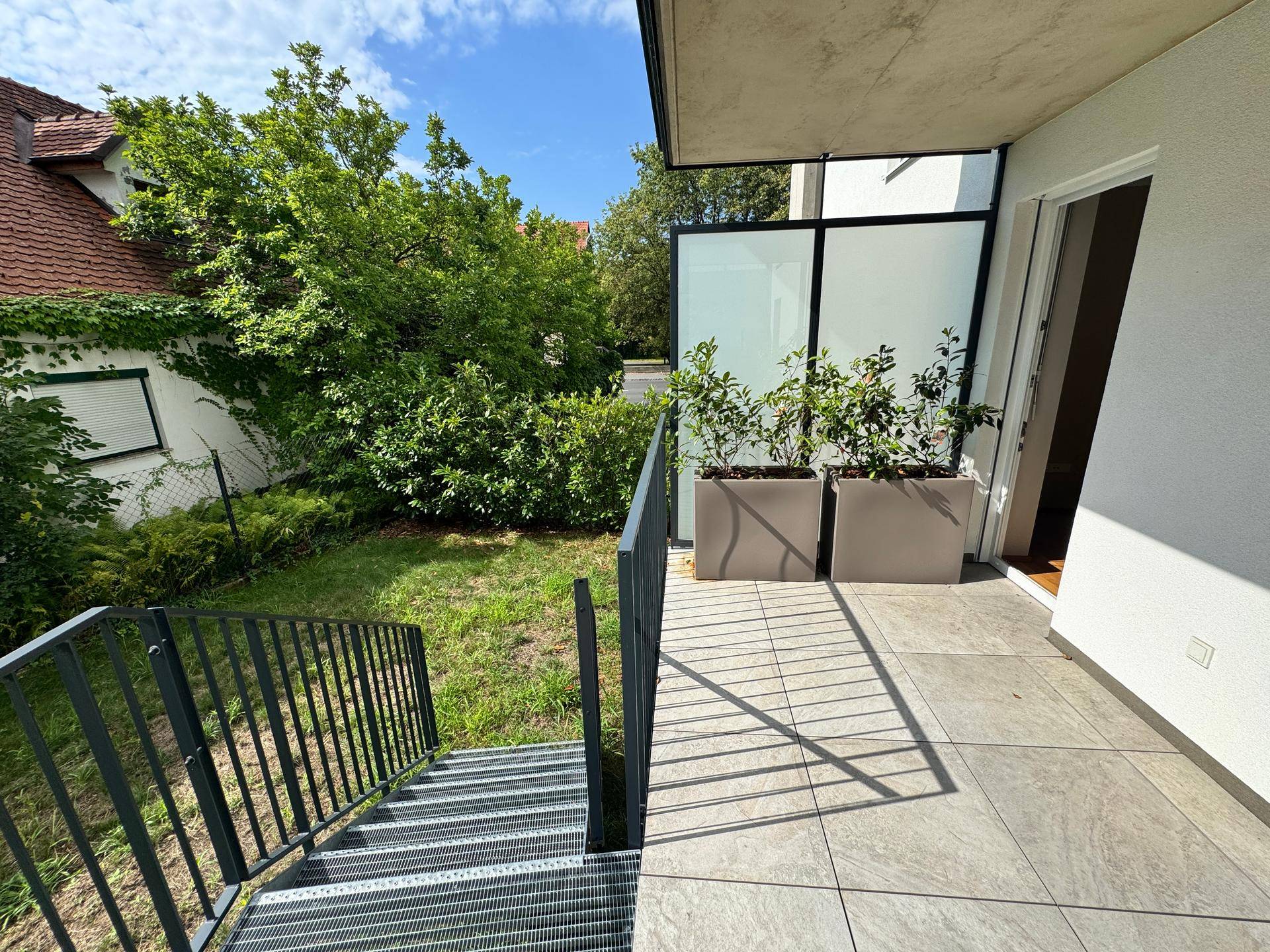 Terrasse mit Treppe zum Garten und Blick auf die grüne Umgebung, bietet viel Privatsphäre.
