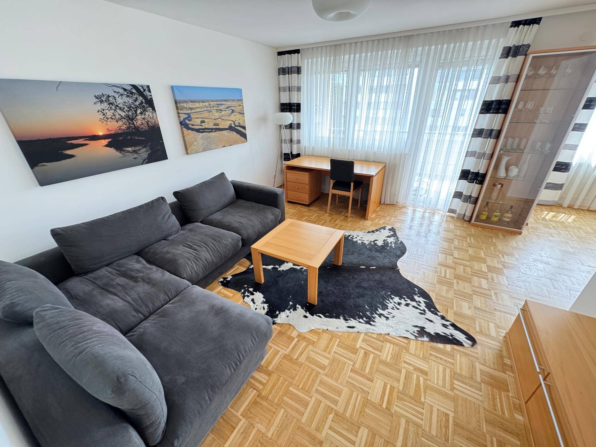 Geräumiges Wohnzimmer mit bequemer Eckcouch, Holztisch und hellem Parkettboden.