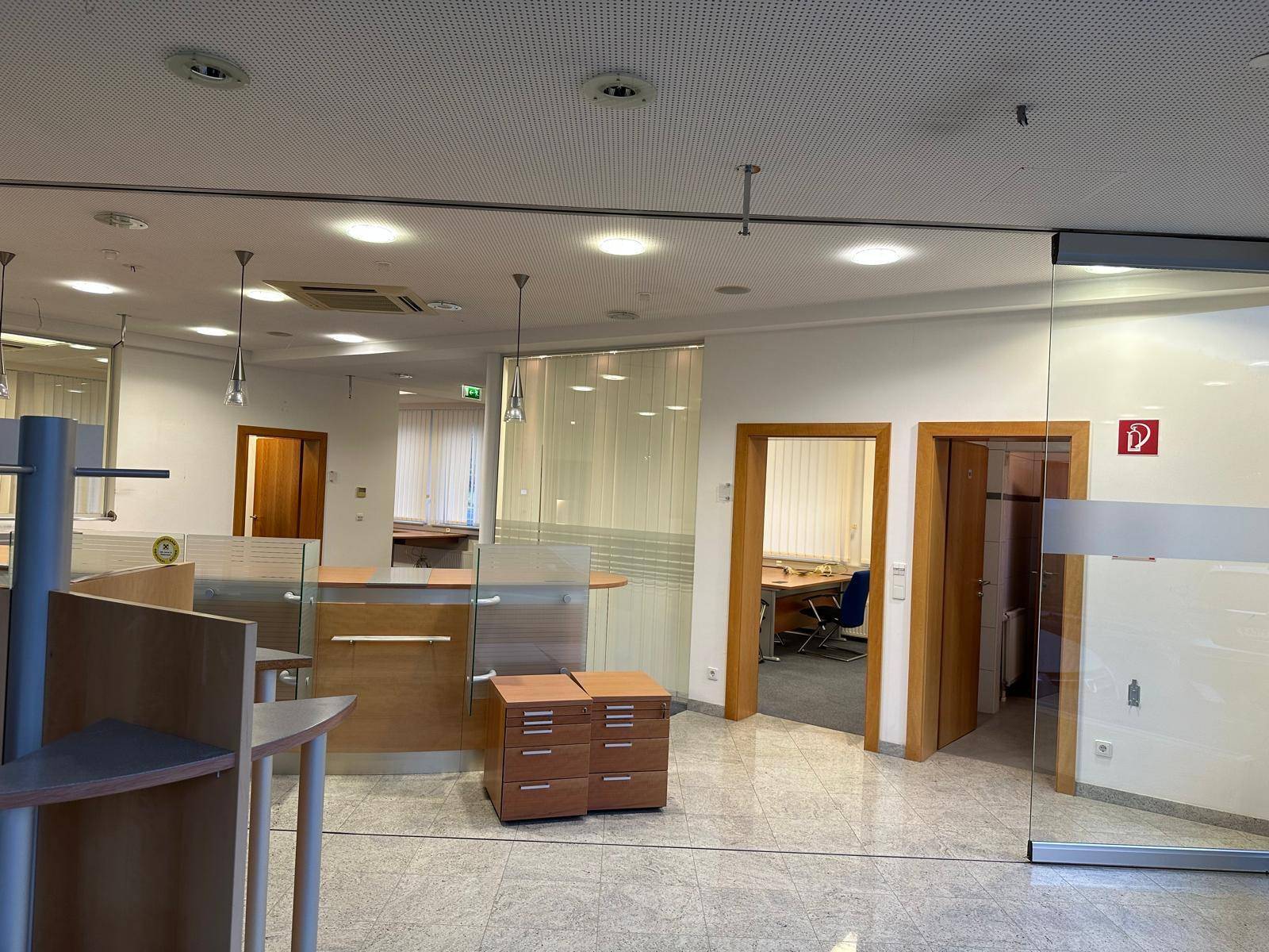 Offener Bürobereich mit modernen Schreibtischen und Zugang zu weiteren Büros.