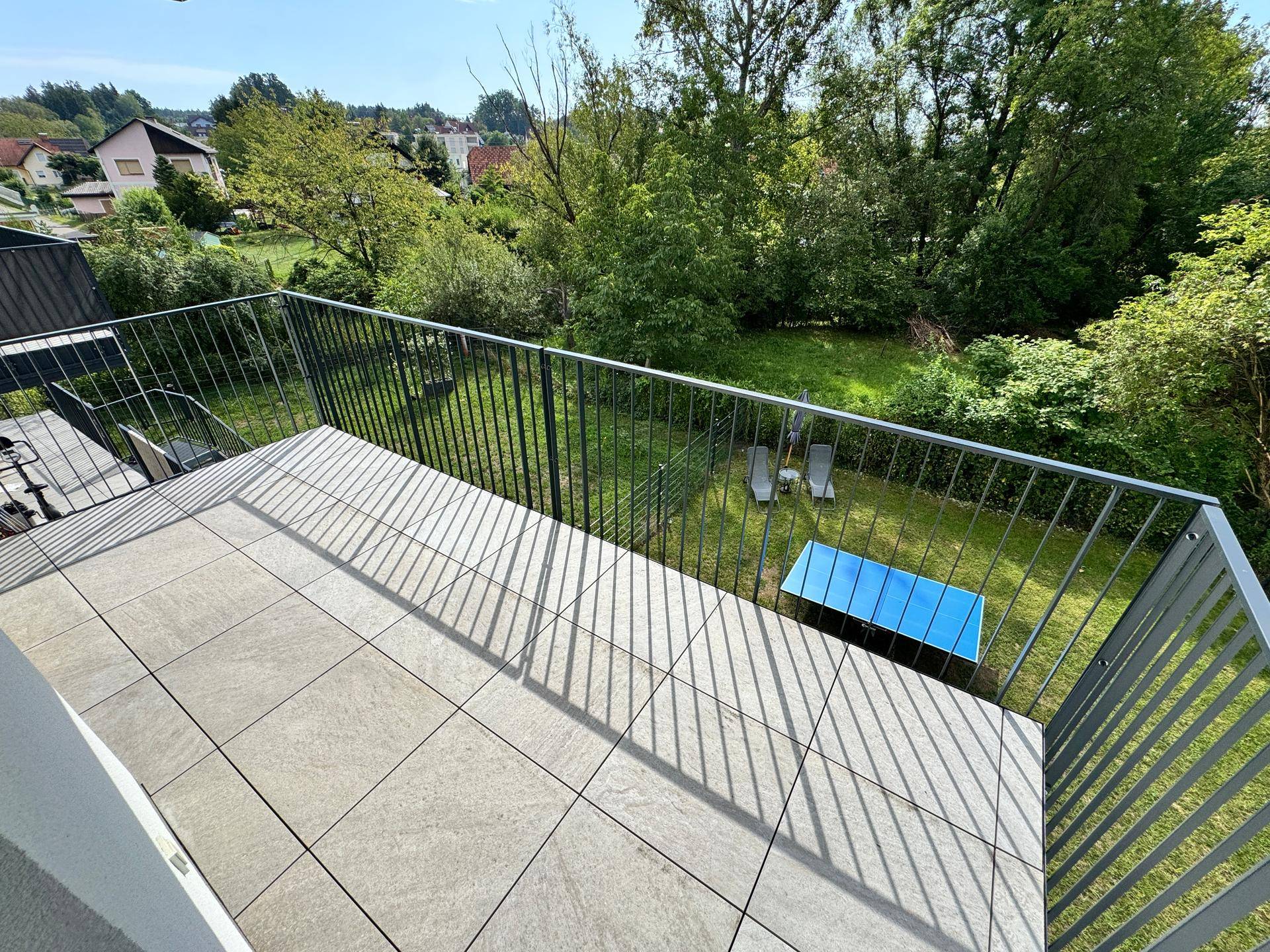 Geräumiger Balkon mit Fliesenboden und Blick auf den Garten und die umliegende Natur.