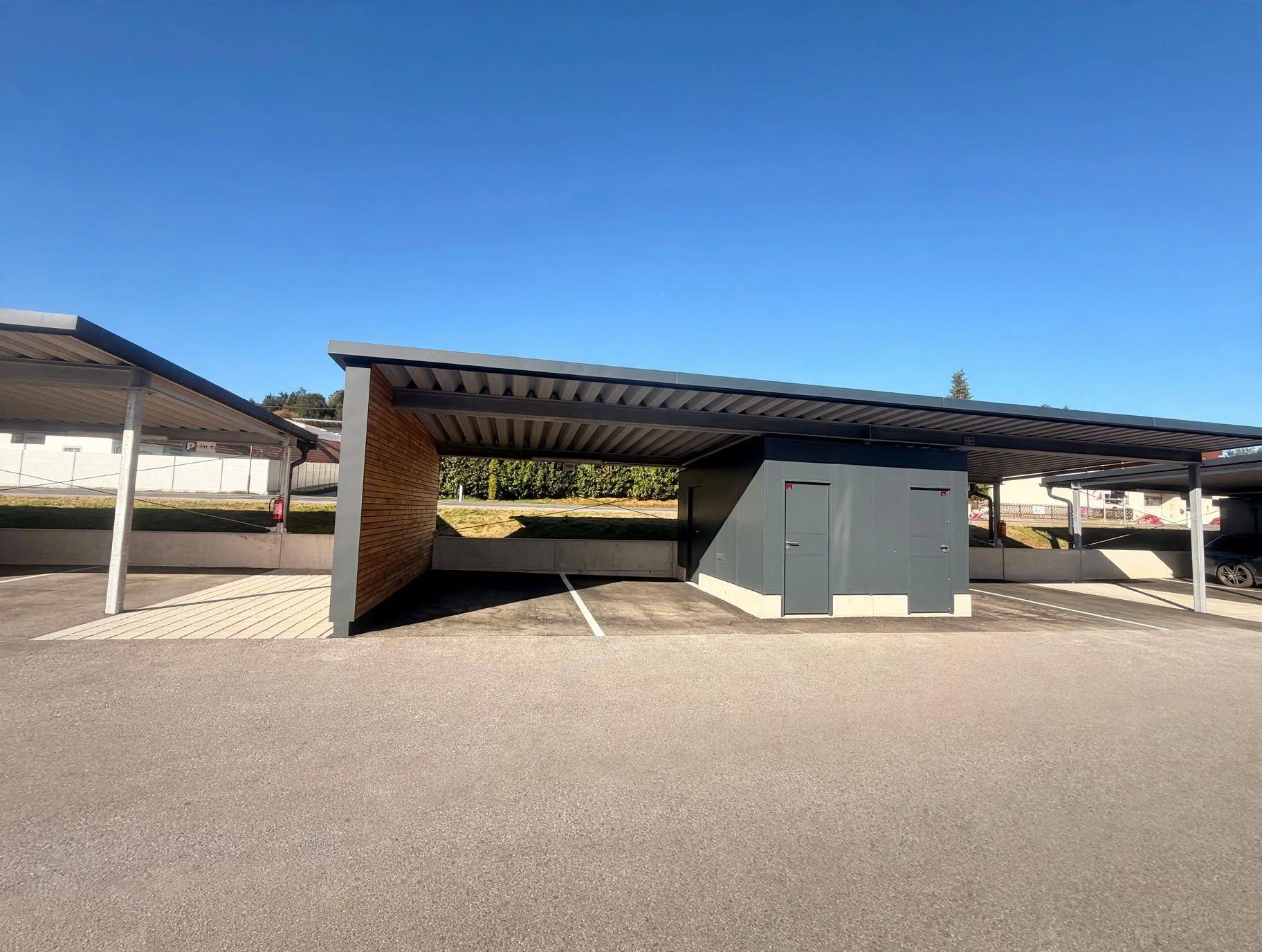 Moderne Carports mit Holzverkleidung und integrierten Abstellräumen auf dem Grundstück.