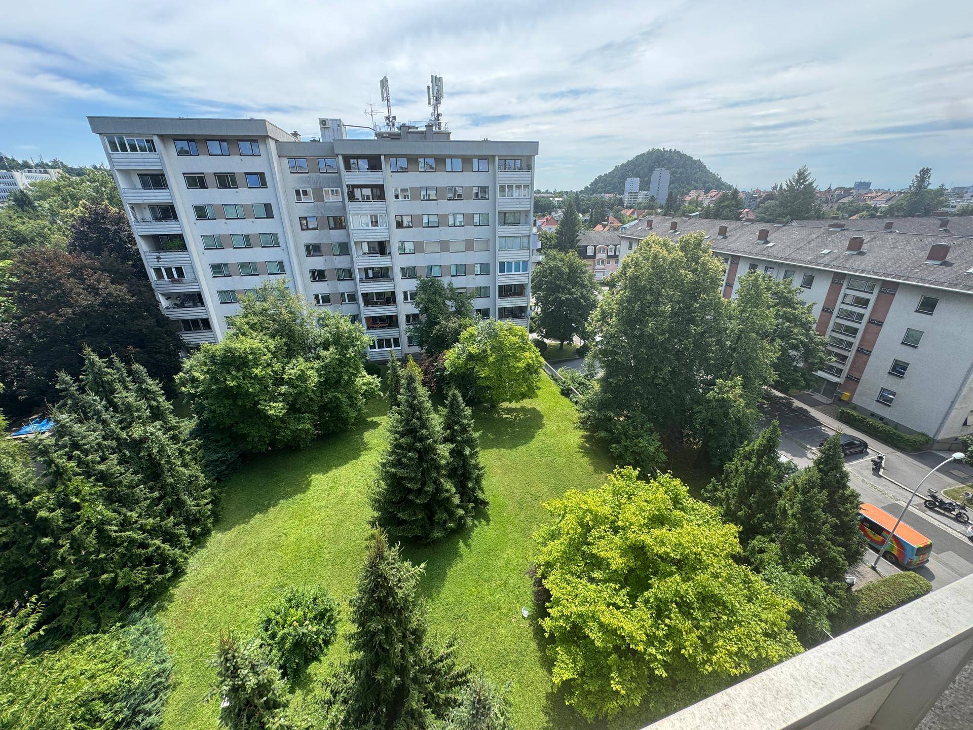 Panoramablick auf eine grüne Parkanlage mit Bäumen und umliegenden Wohngebäuden.