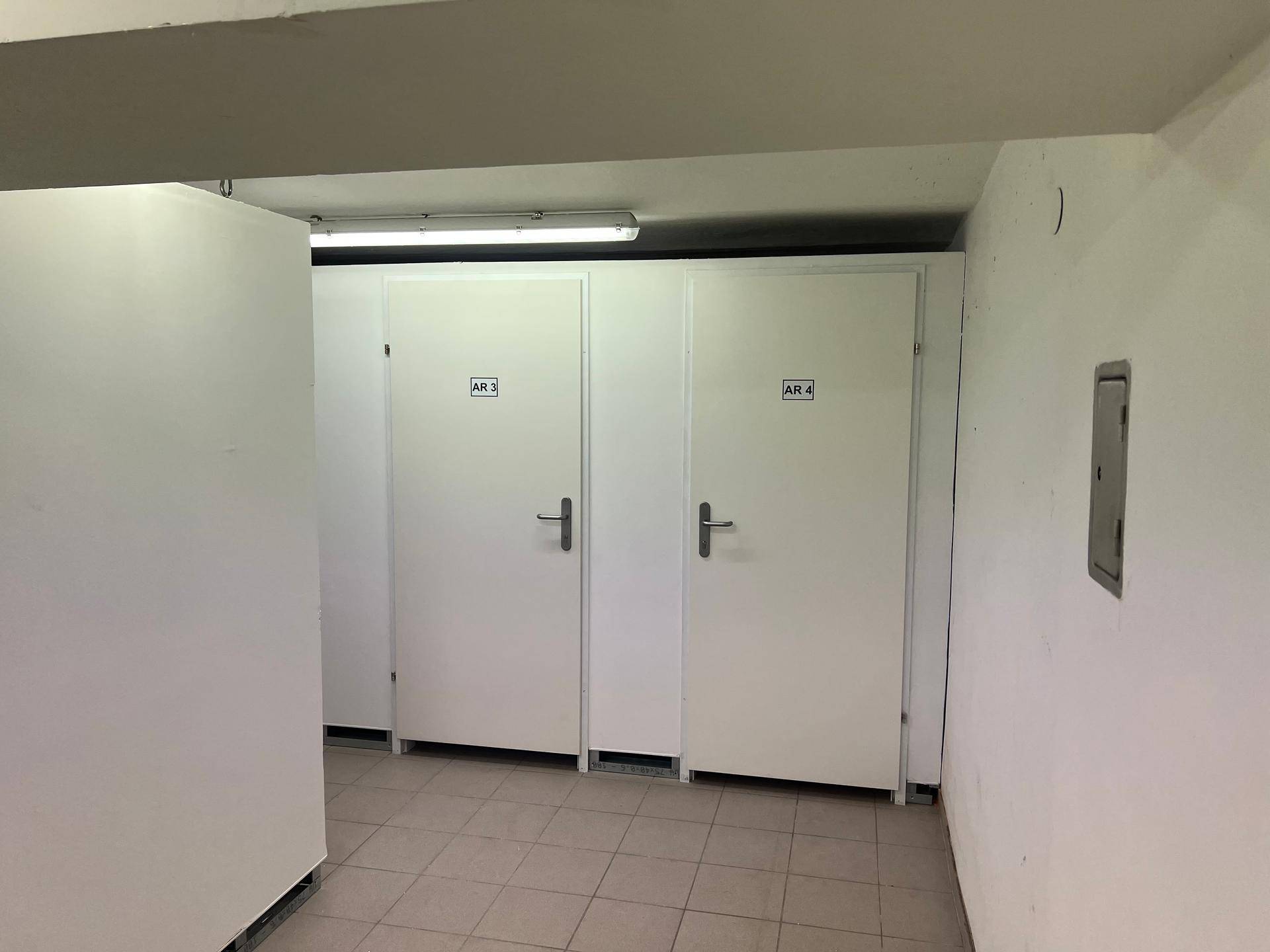 Geräumiger Kellergang mit mehreren weißen Lagerabteilen und einem praktischen, hellen Fliesenboden.