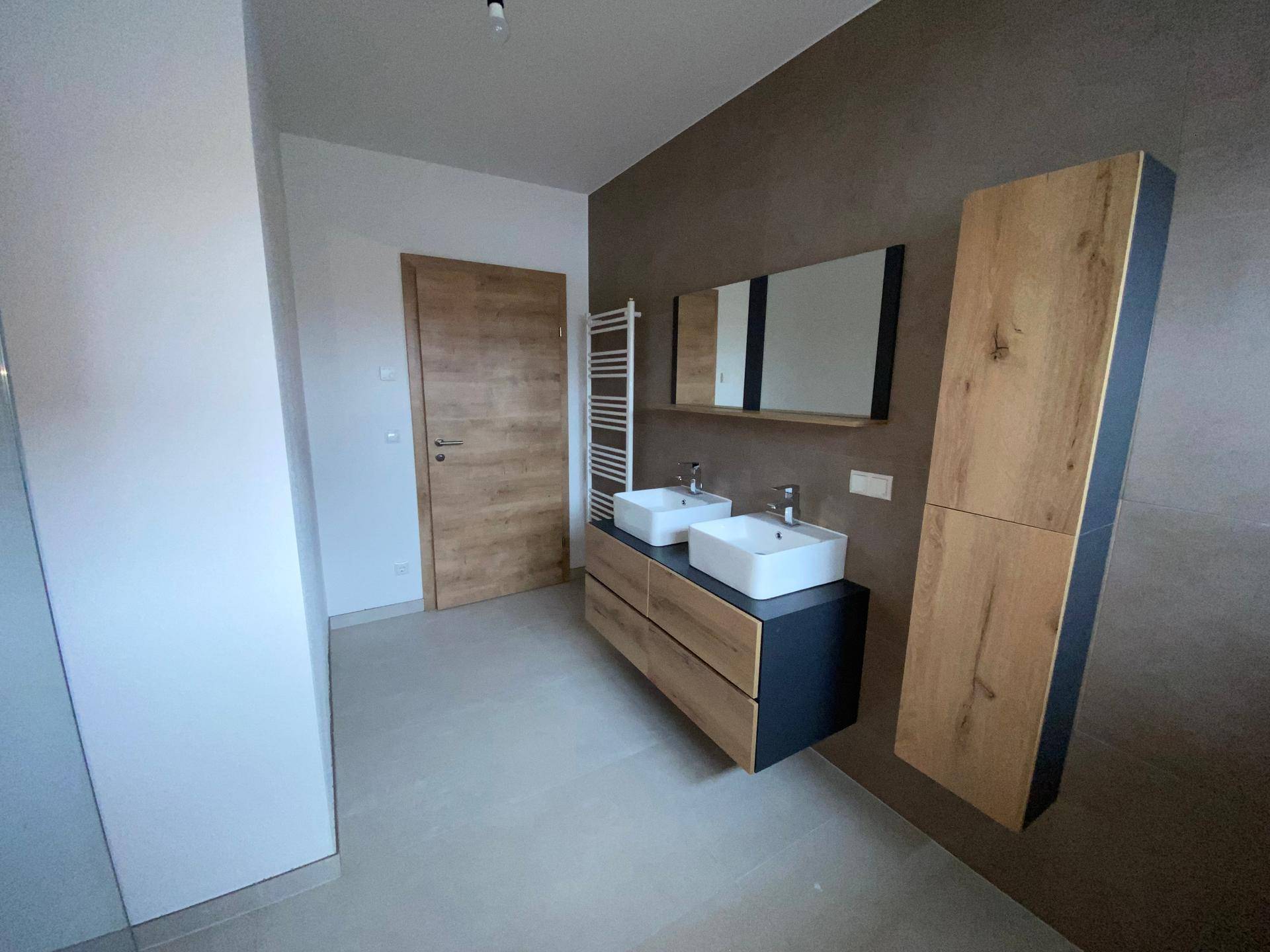 Modernes Badezimmer mit Doppelwaschbecken, Holzmöbeln und beheiztem Handtuchhalter.