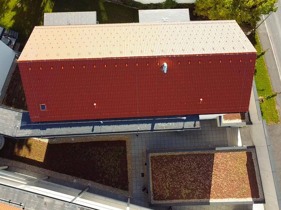 Dachansicht eines Gebäudes mit rotem Dach und begrünten Flachdachbereichen.