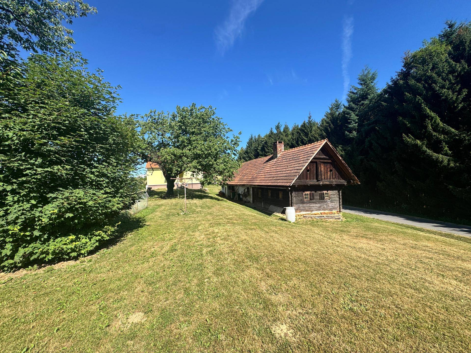 Rustikales Holzhaus auf einem grünen Hügel mit Blick auf die umliegende Landschaft.