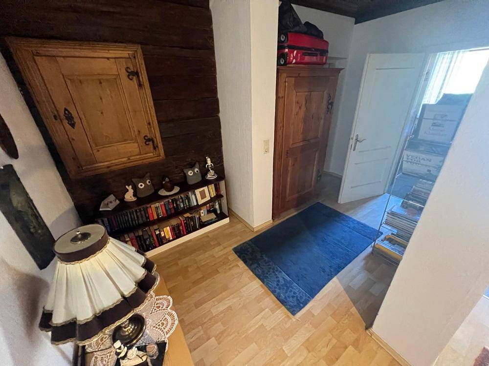 Kleiner Flurbereich mit Holzboden, rustikalen Schränken und Bücherregal.