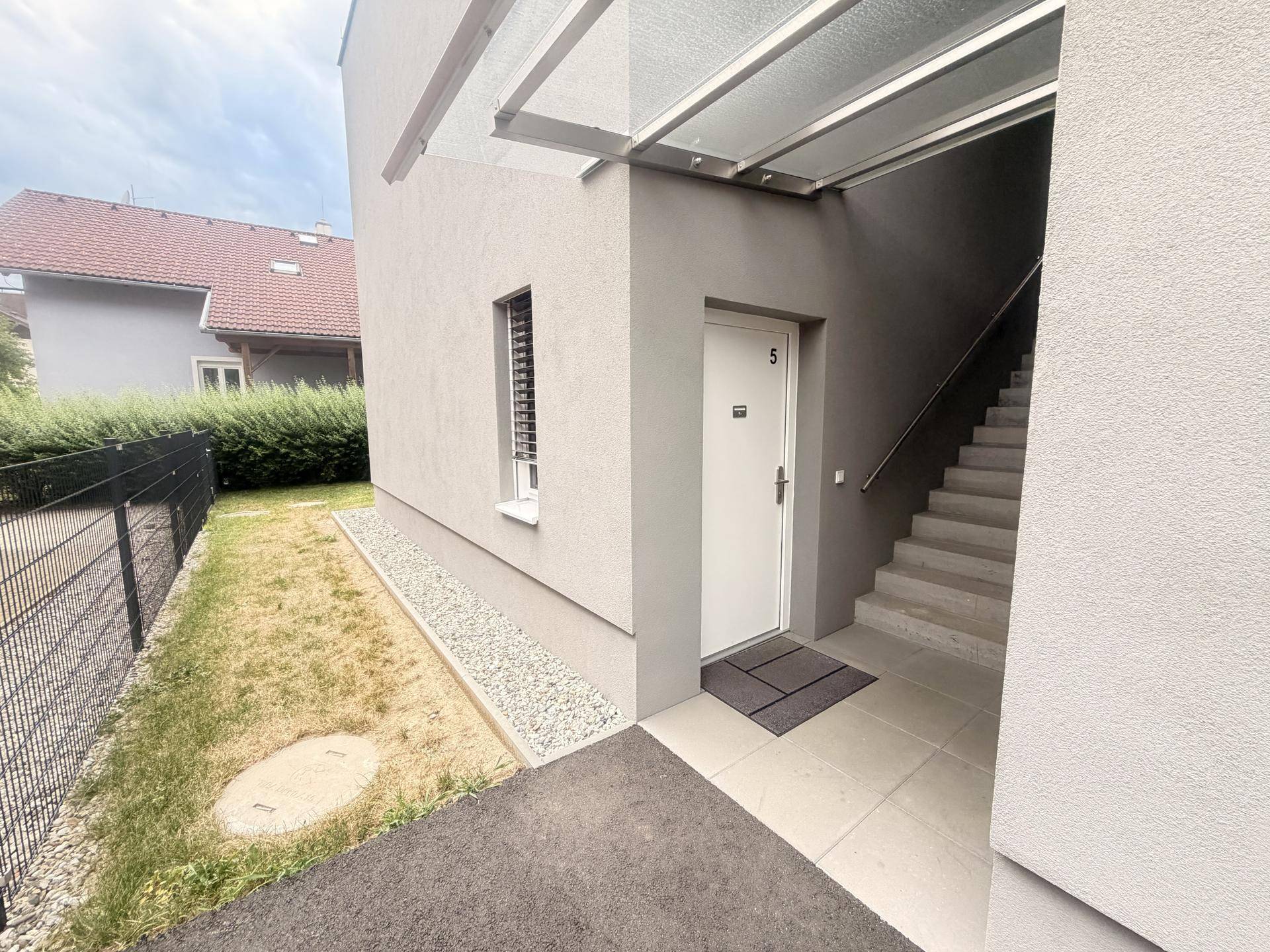 Eingangsbereich eines modernen Gebäudes mit Treppe und Vordach.