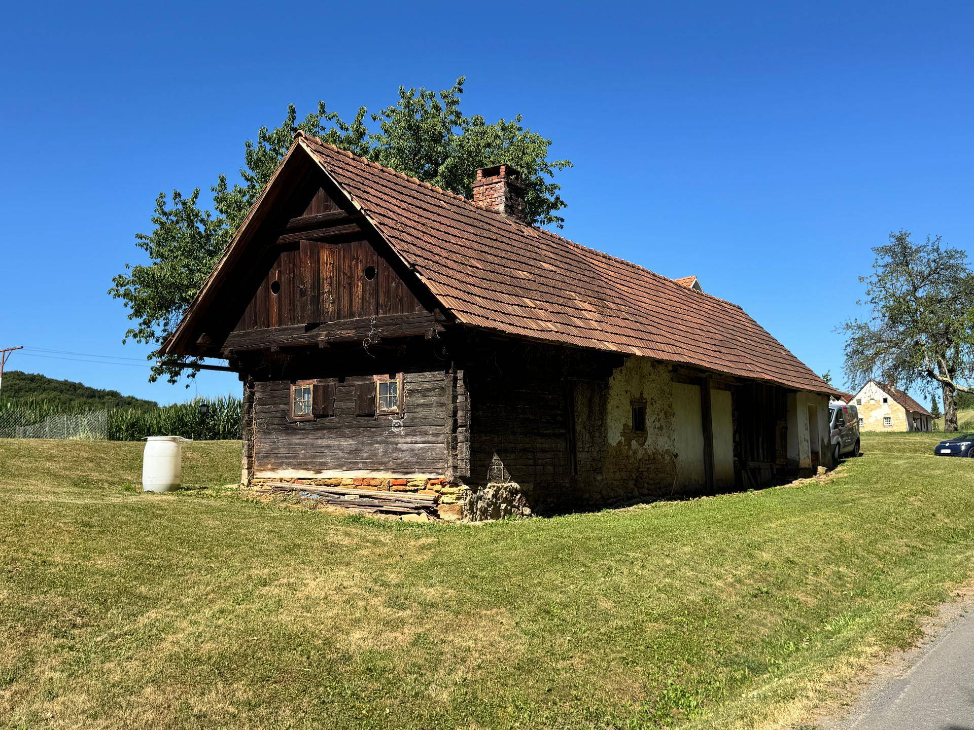 Rustikales Holzhaus mit verwittertem Holz und Steinfundament unter blauem Himmel.