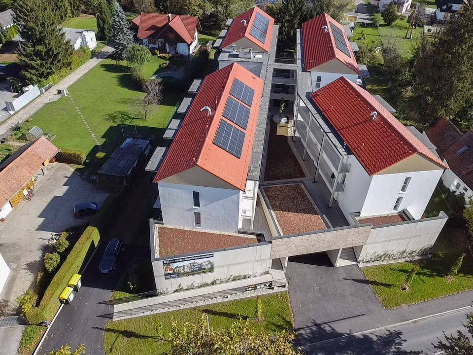 Luftaufnahme einer modernen Wohnanlage mit Photovoltaikanlagen auf den Dächern.