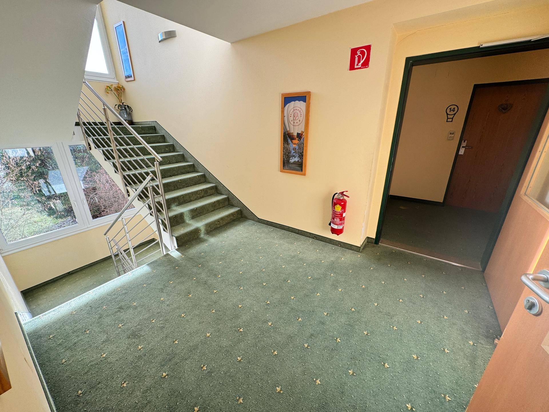 Treppenhaus mit Teppichboden und großen Fenstern.